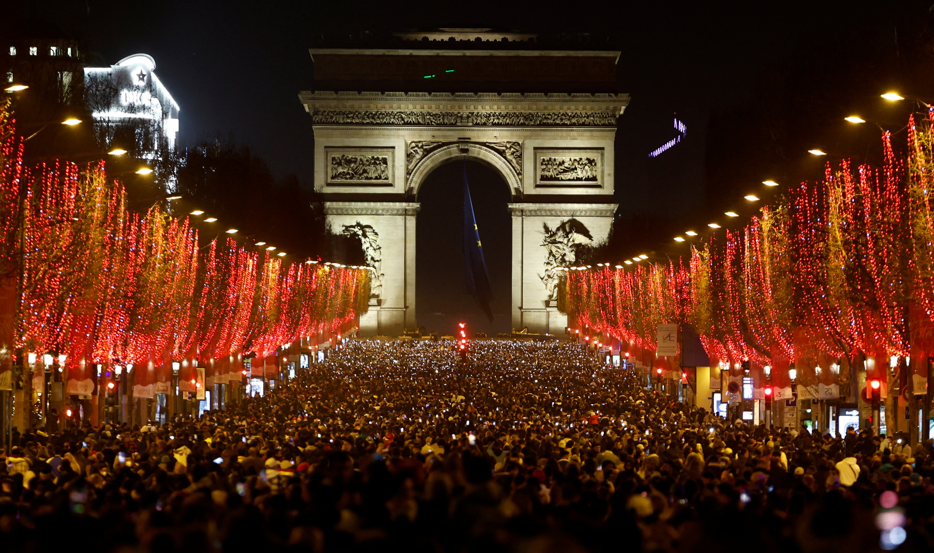 People attend New Year celebrations on the Champs-Elysees avenue as the traditional light show and fireworks have been cancelled due to the spread of the coronavirus disease (COVID-19) in Paris, France, December 31, 2021. REUTERS/Christian Hartmann