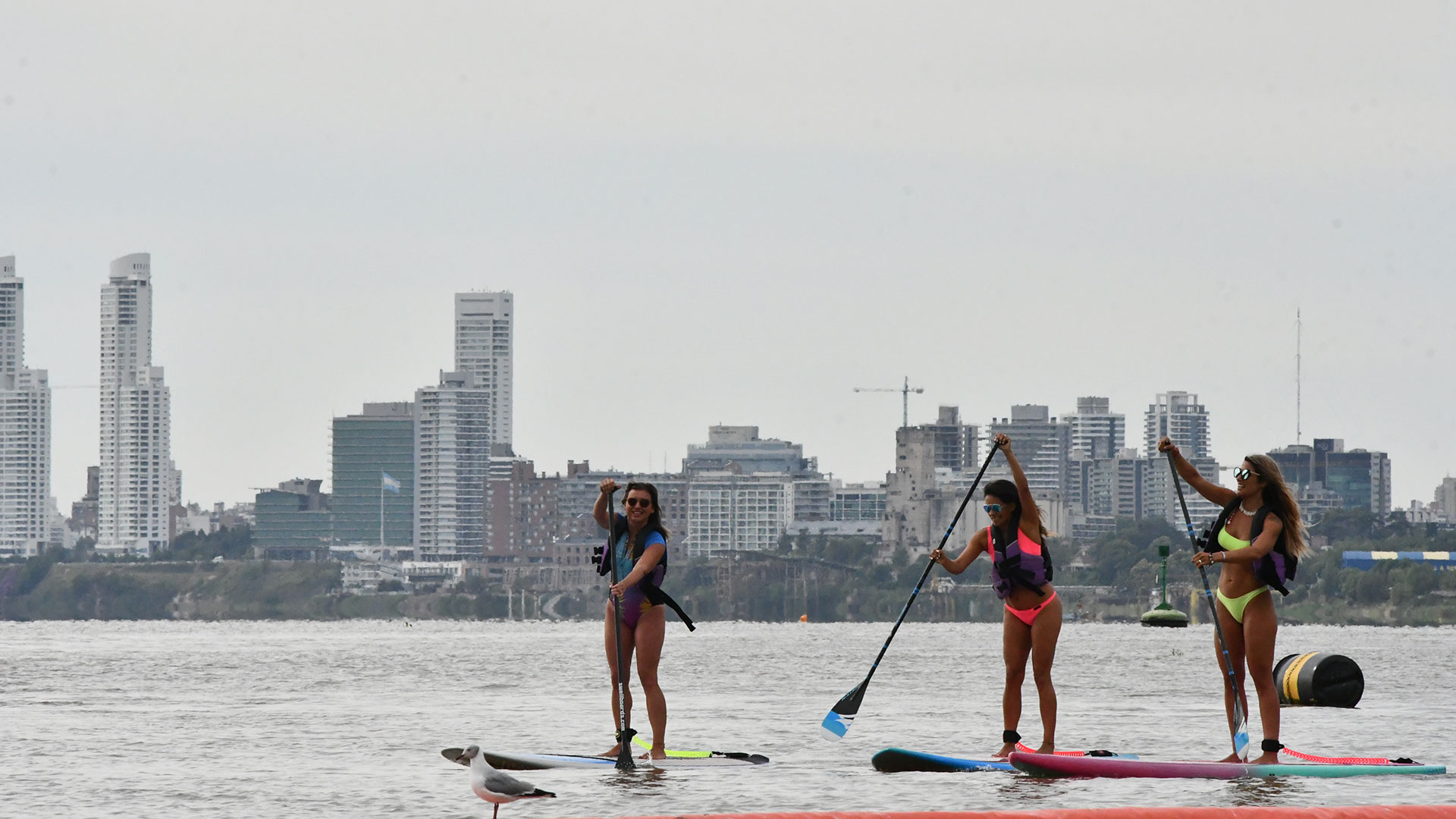 Tres mujeres disfrutan de un día realizando paddle surf en Rosario, uno de los destinos a los que se puede llegar en tren. (ENTE del turismo de rosario)