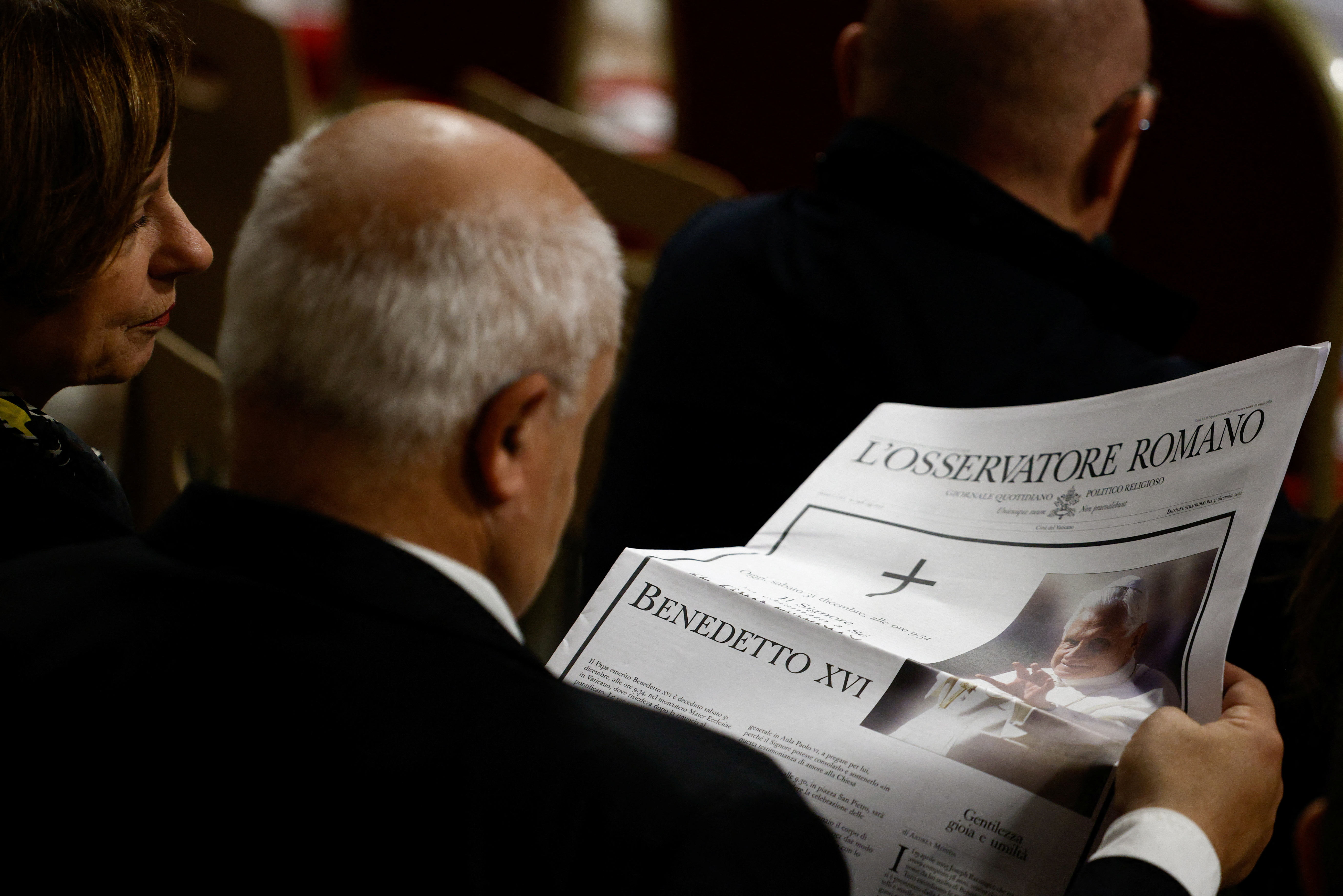 Un fiel lee el periódico "Osservatore Romano" con la noticia de la muerte del ex Papa Benedicto en la Basílica de San Pedro, en el Vaticano, el 31 de diciembre de 2022 (REUTERS)
