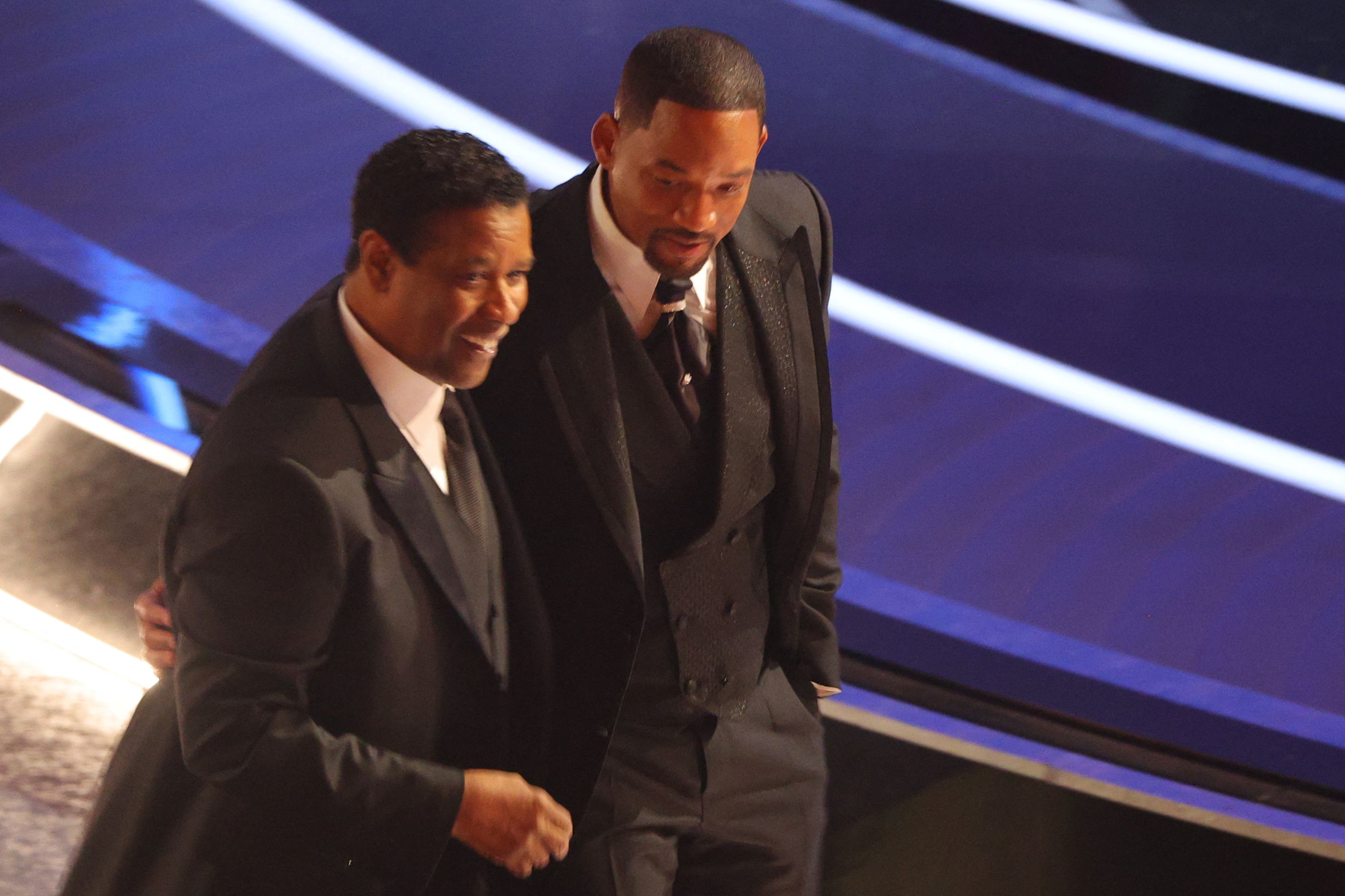 Denzel Washington (L) walks with Will Smith after Smith hit Chris Rock (not pictured) as Rock spoke on stage during the 94th Academy Awards in Hollywood, Los Angeles, California, U.S., March 27, 2022. REUTERS/Brian Snyder