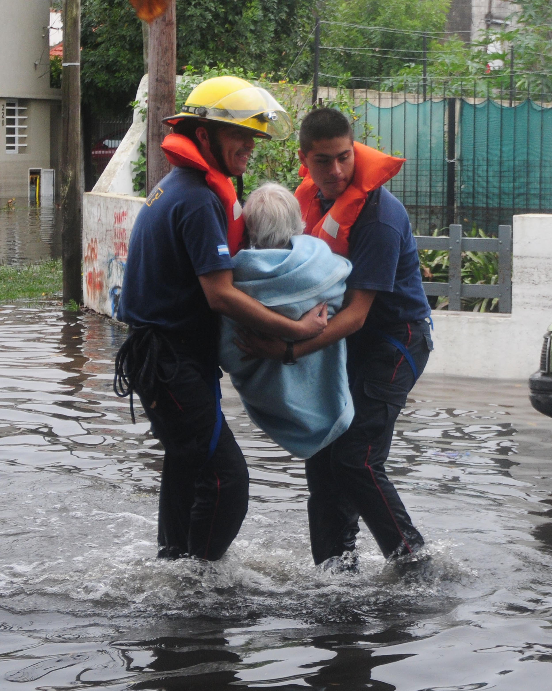 Dos bomberos llevan a una anciana. El saldo oficial de la inundación fue 89 muertos (DyN)