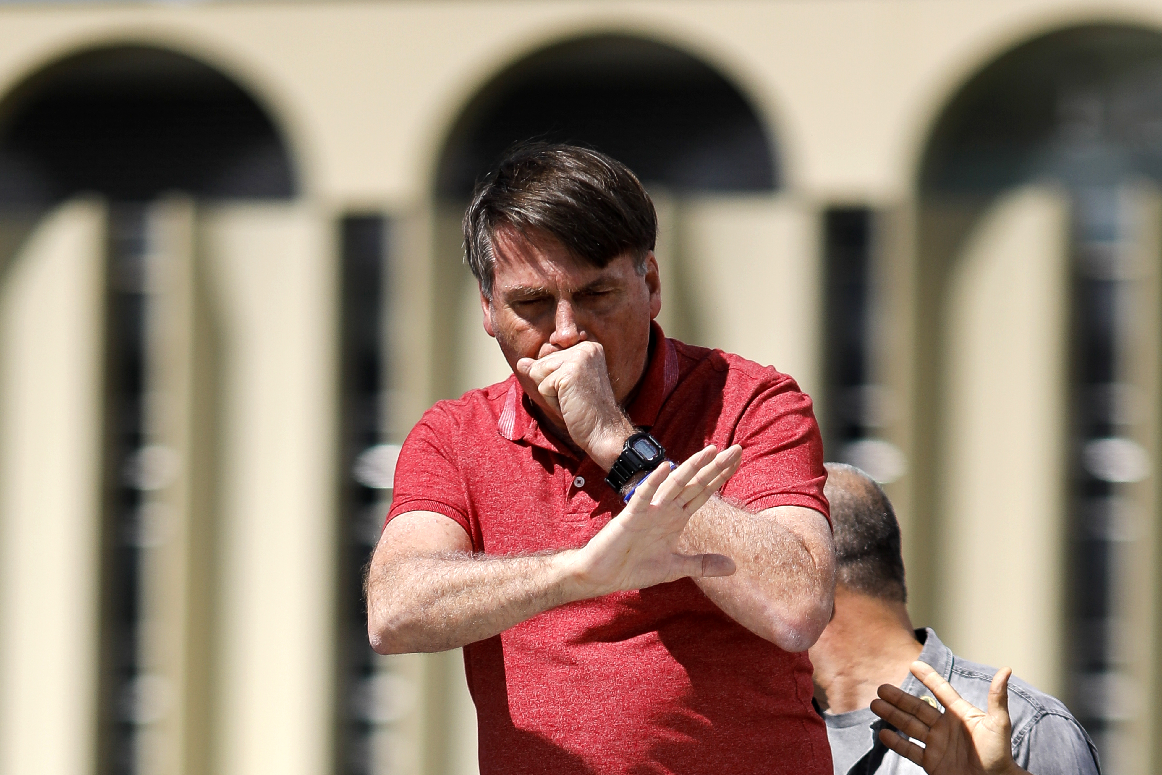 Bolsonaro tosiendo durante un discurso ante sus seguidores que protestaron contra los confinamientos impuestos en algunos estados, el 19 de abril pasado. A contramano de los recomendado por la OMS de toser sobre los codos, el presidente tose en su mano (Photo by Sergio LIMA / AFP)