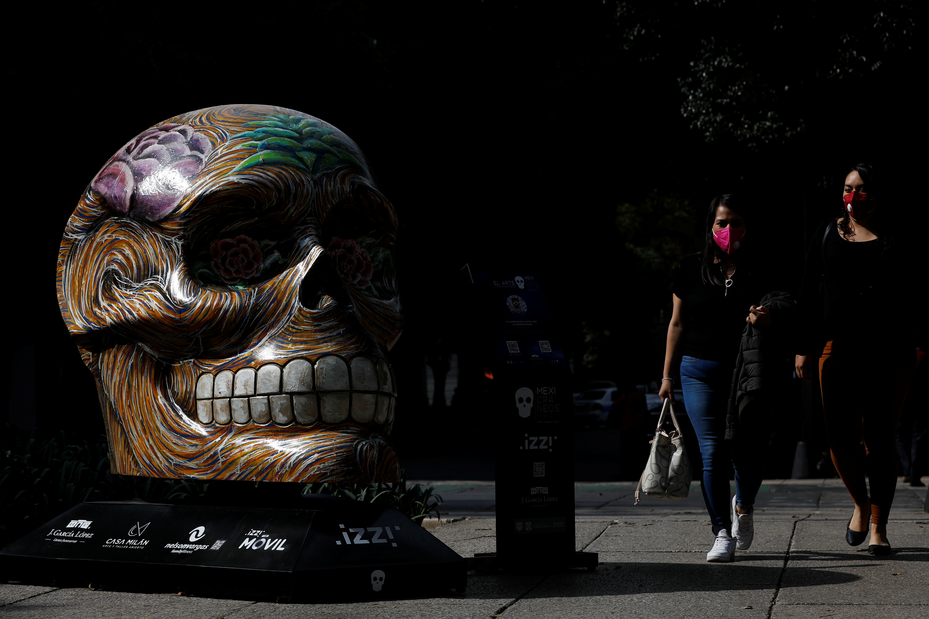People walk by a colorful skull exhibited at Reforma avenue, as part of the festivities in the lead-up to the Day of the Dead celebration, in Mexico City, Mexico October 13, 2020. REUTERS/Carlos Jasso