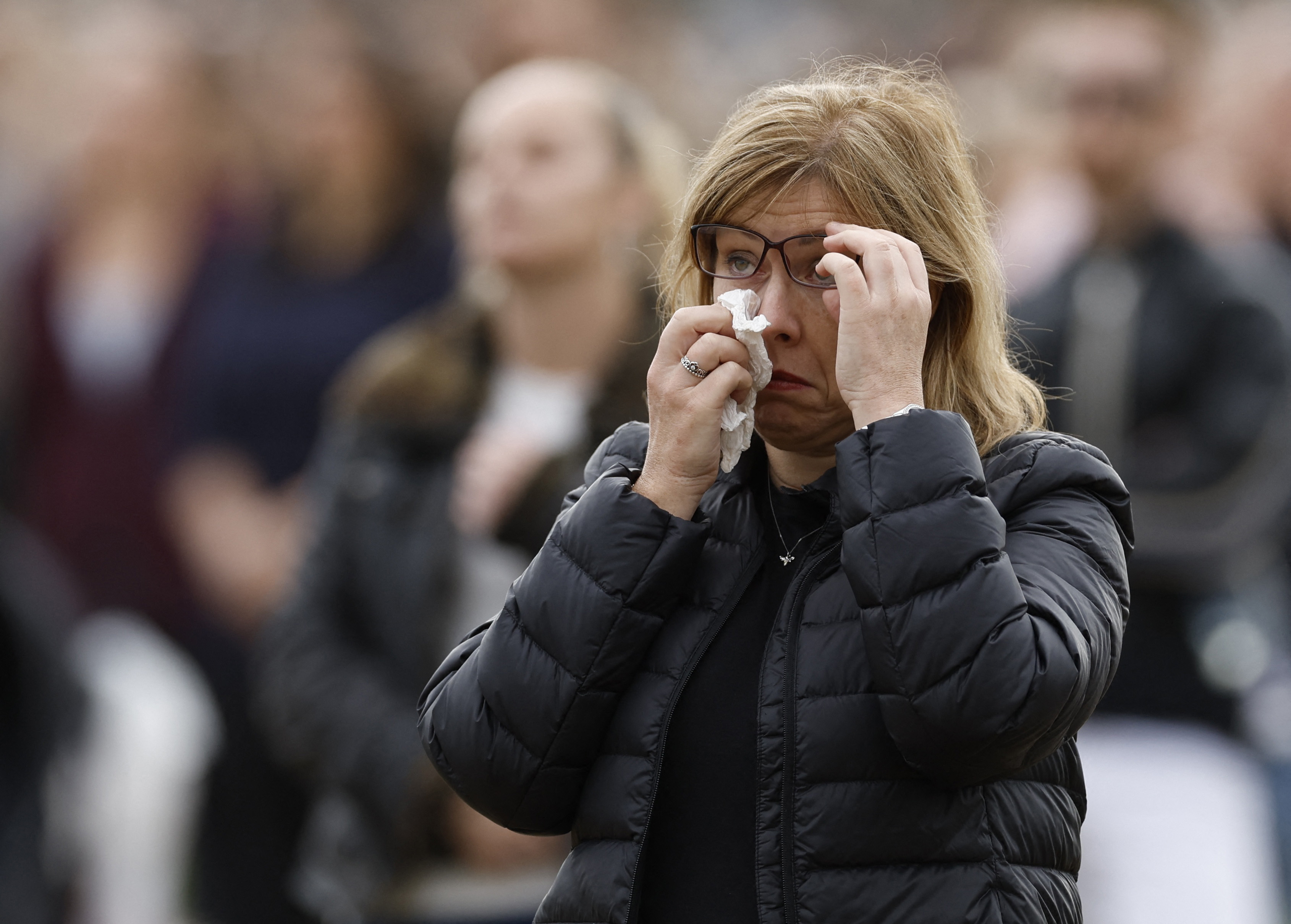 Una mujer se seca las lágrimas mientras ve la transmisión en vivo del funeral de Isabel II.