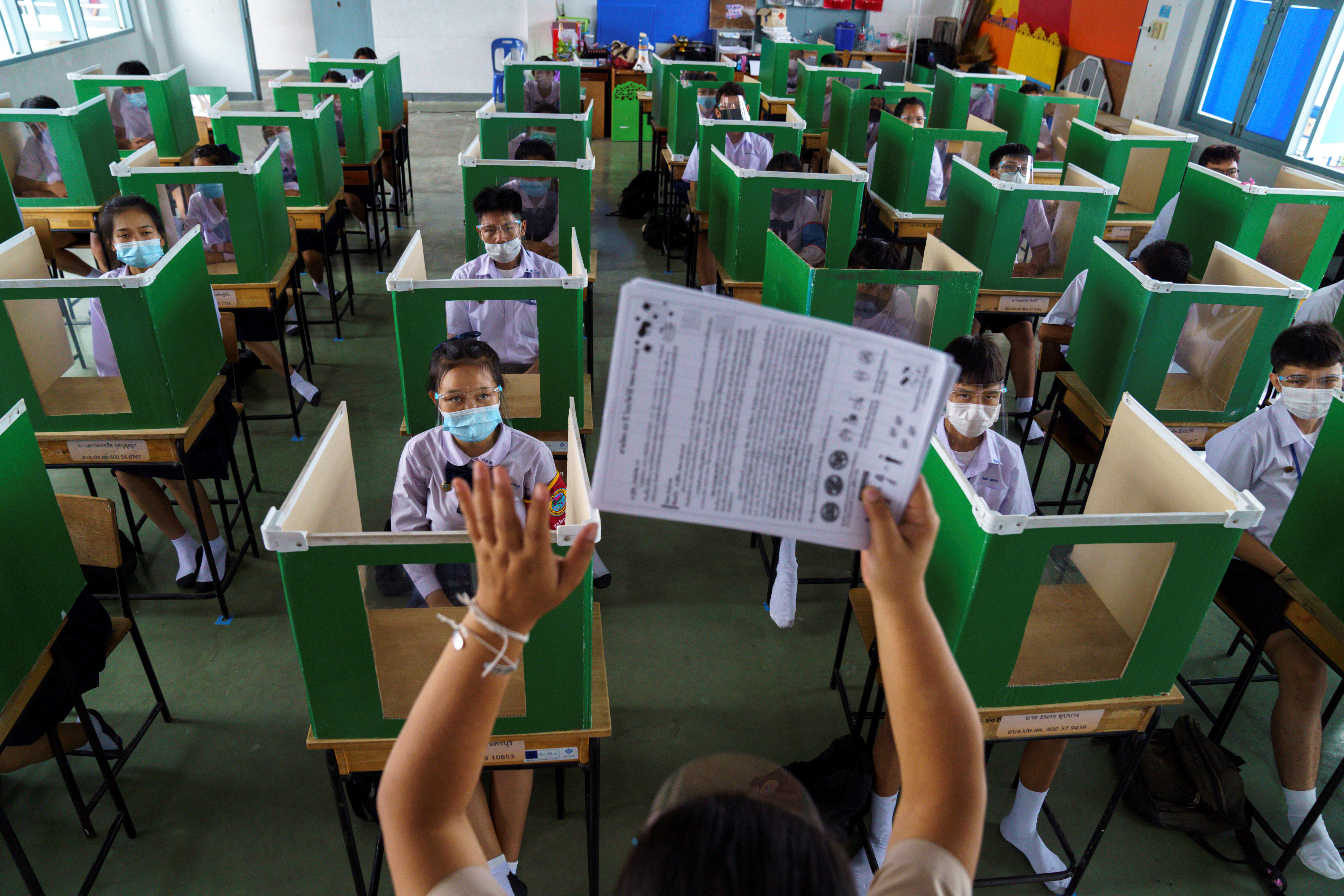 Estudiantes de la escuela Sam Khok en Pathum, Tailandia, sentados en escritorios modificados para prevenir la difusión del coronavirus, tras el fin de la cuarentena y la reapertura de los colegios (REUTERS/Athit Perawongmetha)