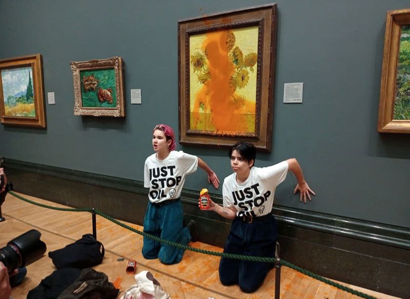 Activistas del grupo "Just Stop Oil" con sus manos pegadas a la pared tras arrojar sopa al cuadro "Los girasoles" de van Gogh en la National Galllery de Londres (Reuters)