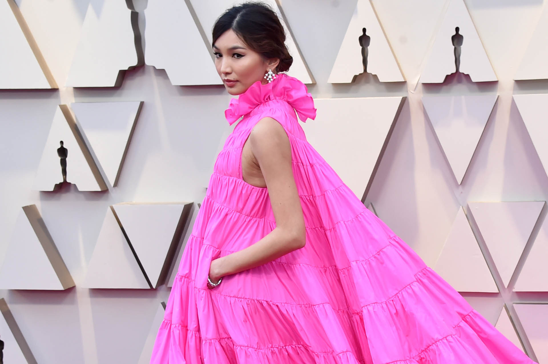 La actriz Gemma Chan sorprendió en la alfombra roja con un vestido de Valentino en color fucsia sin mangas y cuello con volados