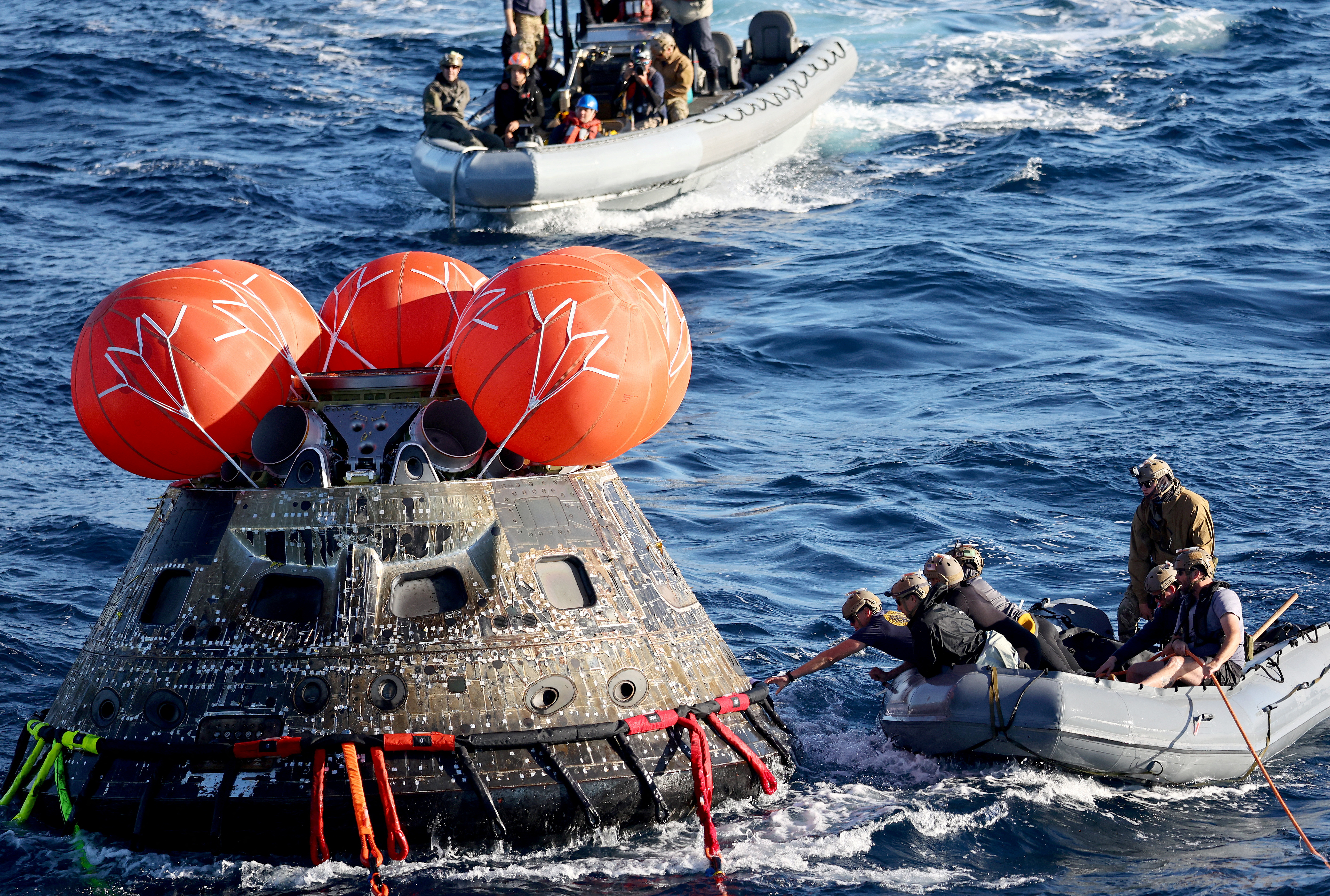 U.S. Navy divers protect NASA's Orion capsule during recovery operations after the successful Artemis I lunar mission (REUTERS via Mario Dama/Poole).
