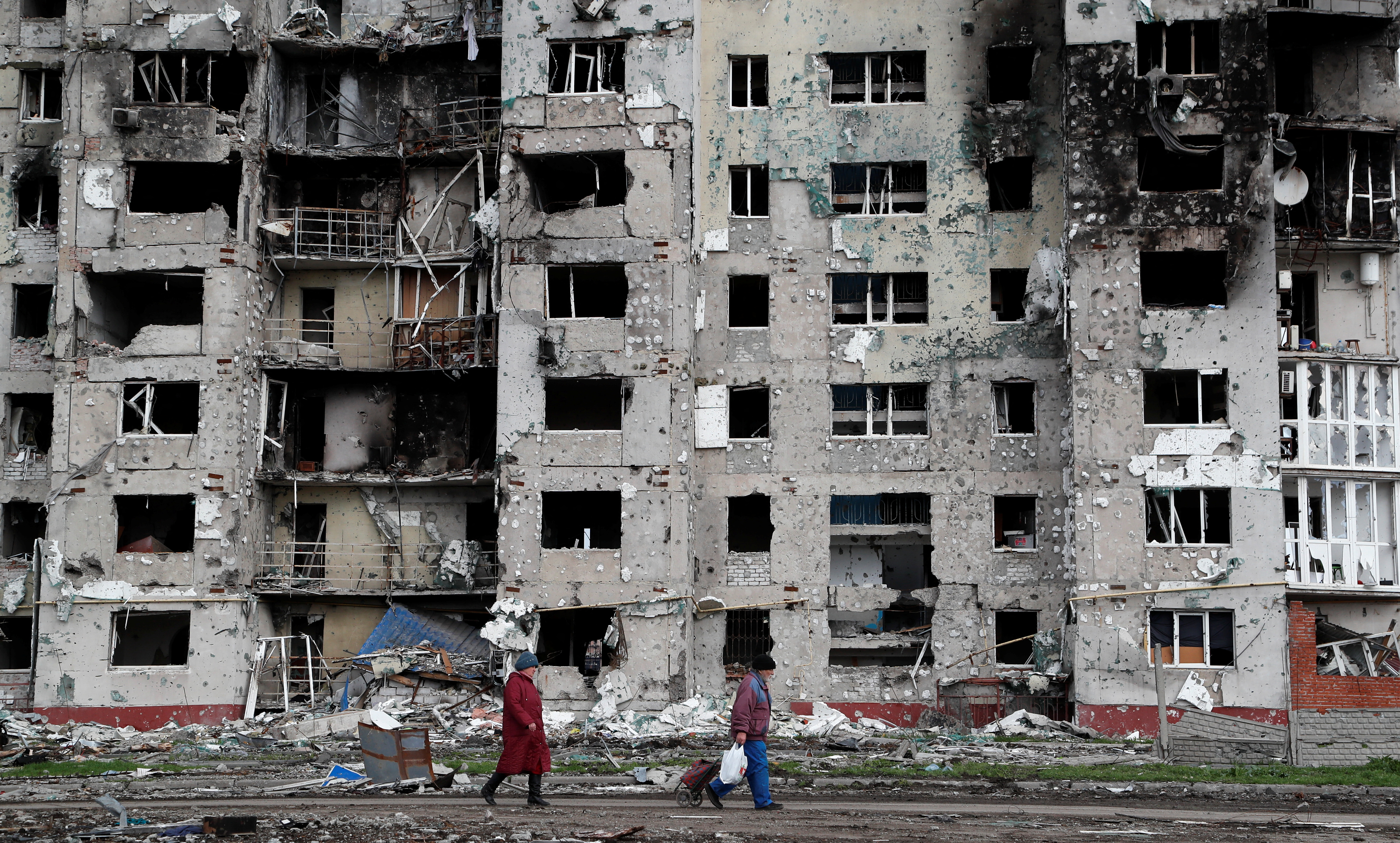 Gente camina frente a edificios destruidos en Mariupol, Ucrania (REUTERS/Alexander Ermochenko)