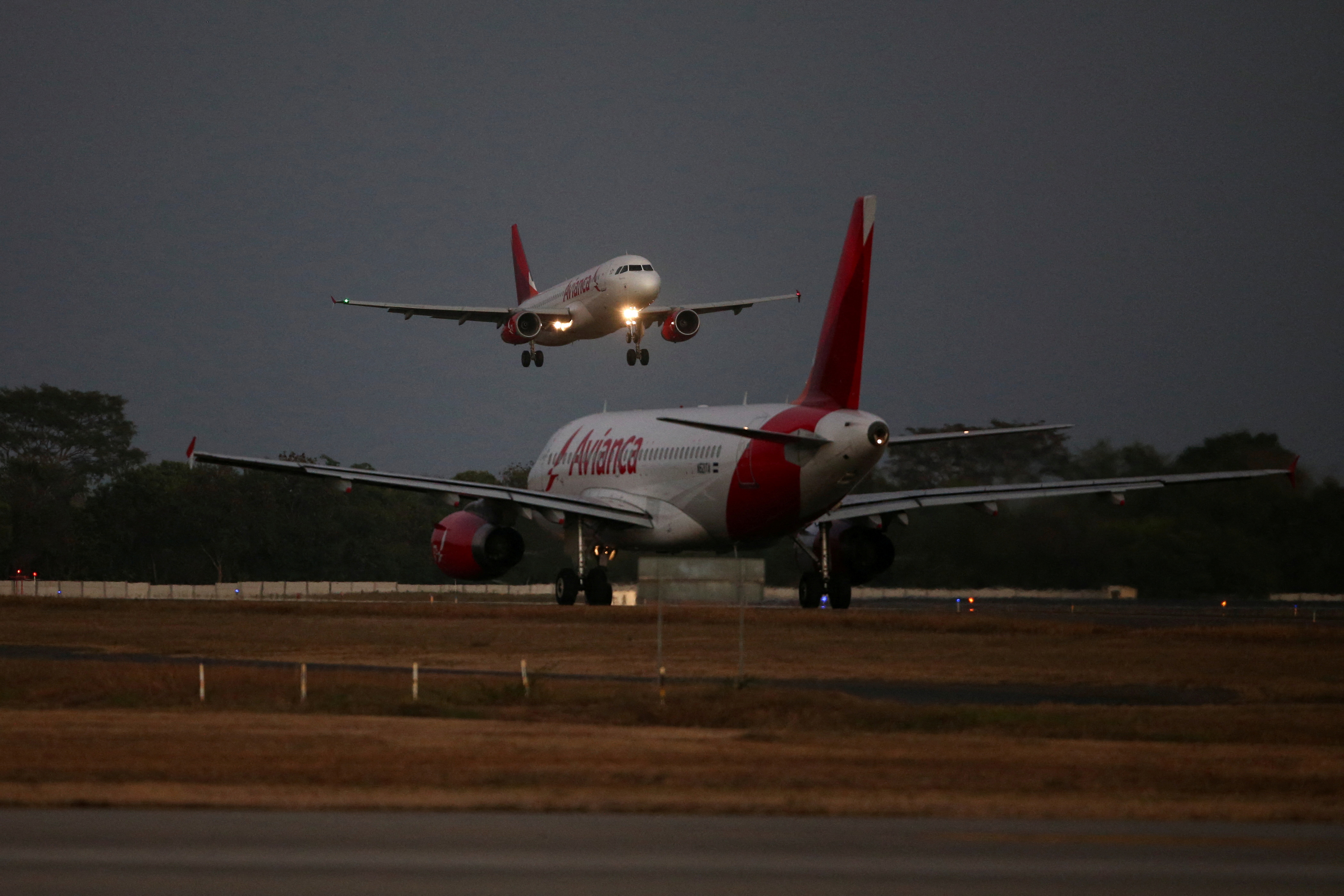 An Avianca Airlines plane lands as another prepares to take off at the San Oscar Arnulfo Romero International Airport in San Luis Talpa, El Salvador, February 8, 2022. REUTERS/Jose Cabezas