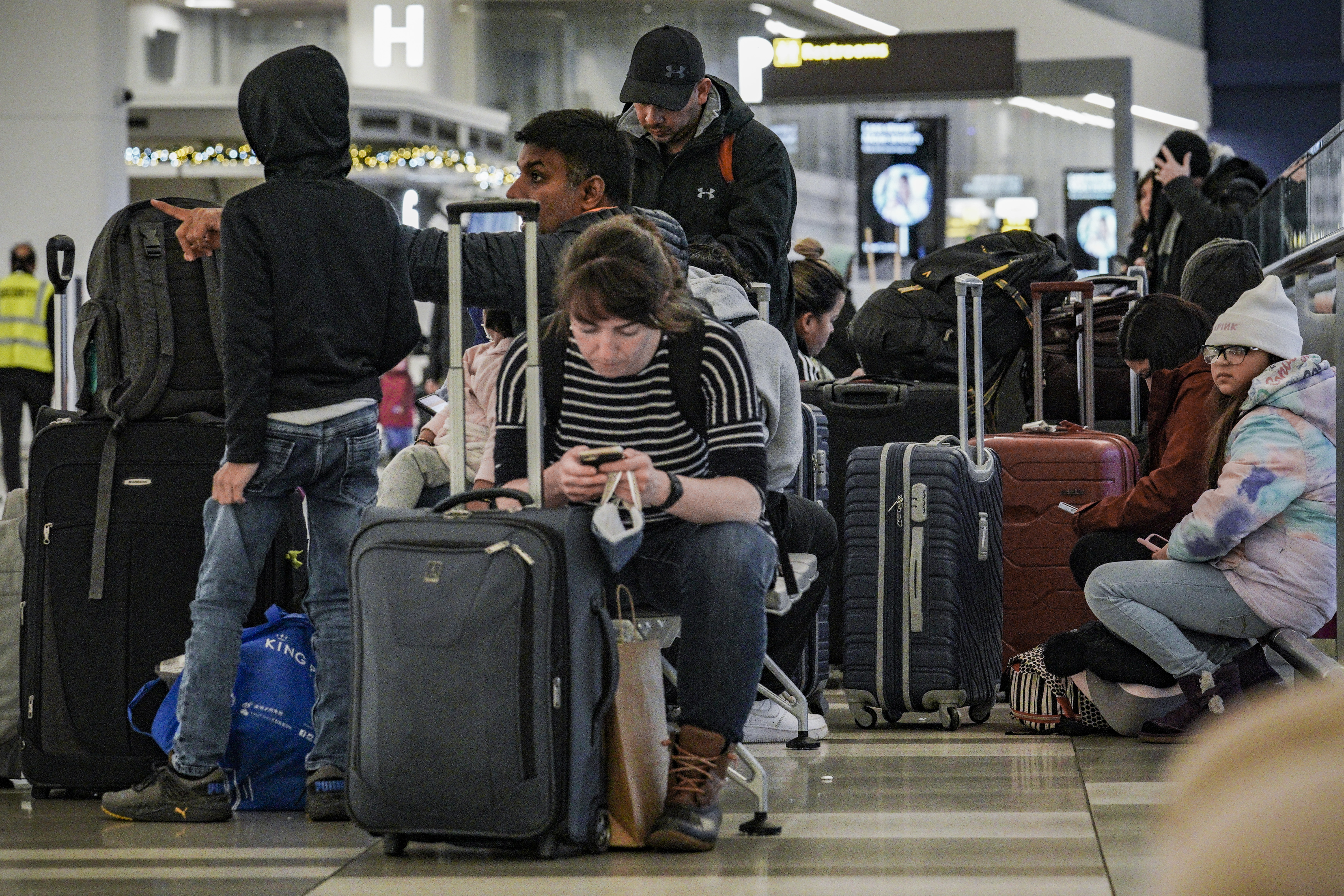 Pasajeros de Southwest Airlines se sientan con su equipaje en la zona de registro debido a retrasos y cancelaciones en el aeropuerto Laguardia, en Nueva York (AP Foto/Bebeto Matthews)