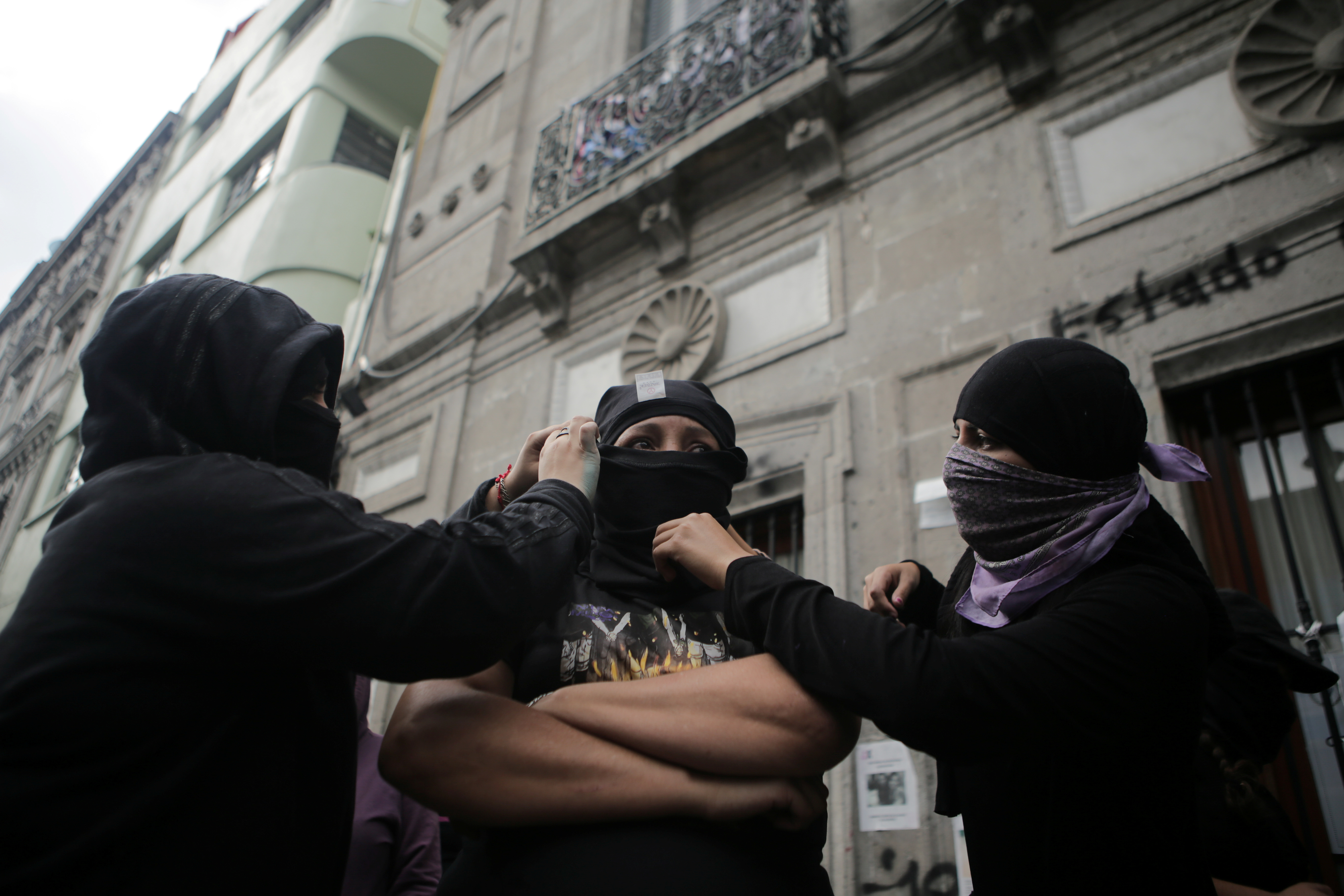 Integrantes de un colectivo feminista ayudan a Yesenia Zamudio, madre de una víctima de violencia de género, a cubrirse el rostro frente a las instalaciones del edificio de la Comisión Nacional de Derechos Humanos, en apoyo a las víctimas de violencia de género, en la Ciudad de México, México, 11 de septiembre de 2020.