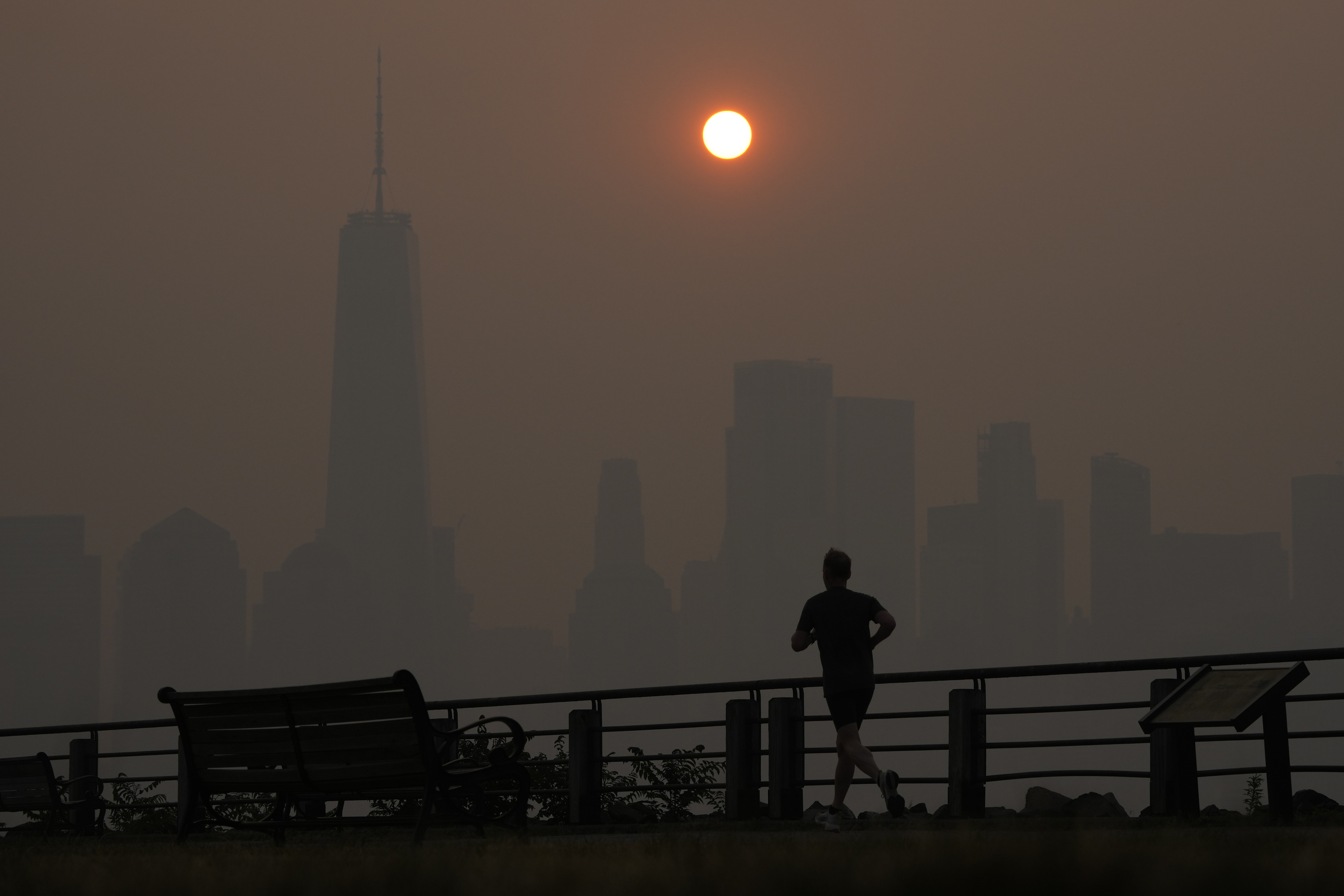 Un hombre corre al amanecer pese al humo este jueves mientras el sol se levanta sobre el firmamento de Manhattan (AP)