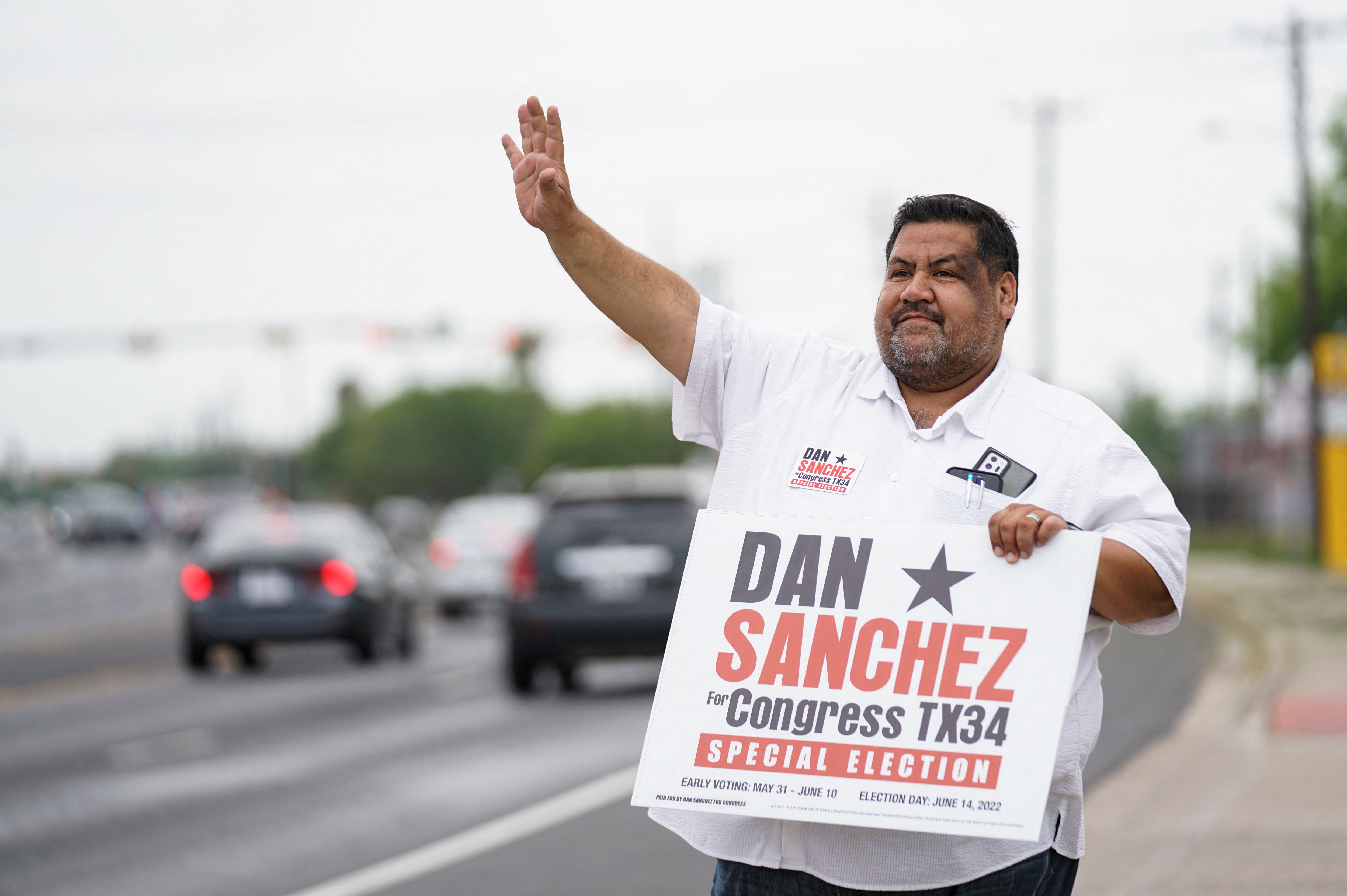 Democrat Dan Sanchez, who running for the vacant 34th congressional district seat, waves at motorists passing by a polling site in Brownsville, Texas, U.S., June 14, 2022. REUTERS/Veronica G. Cardenas