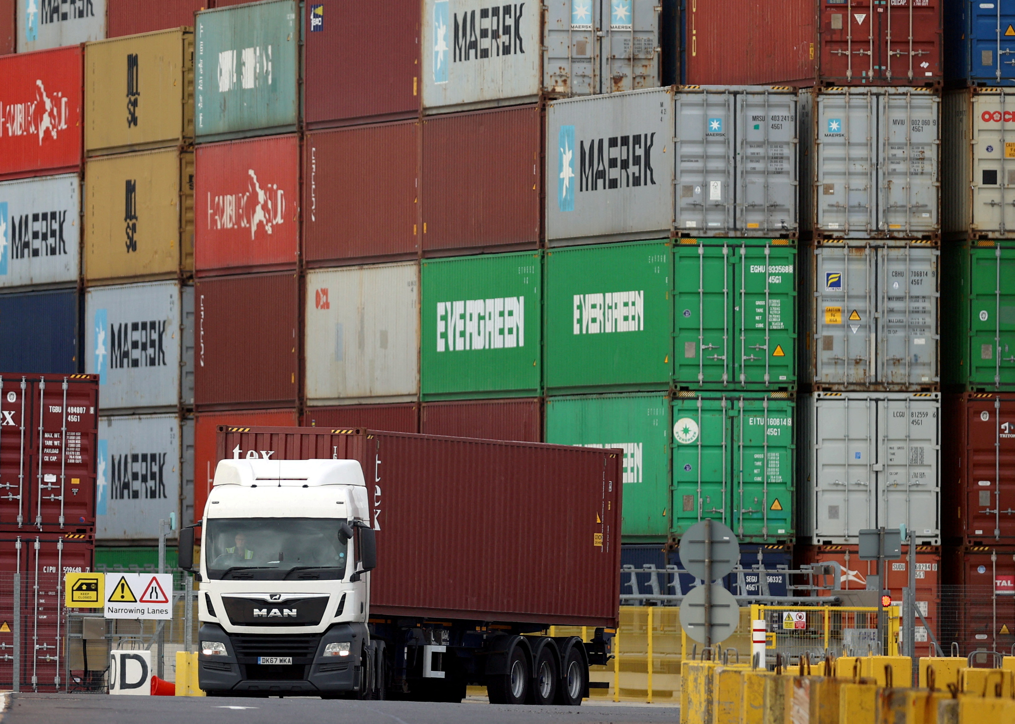 Un camión pasa por delante de contenedores de transporte apilados en el puerto de Felixstowe, Gran Bretaña, 13 de octubre de 2021. REUTERS/Hannah McKay/Archivo