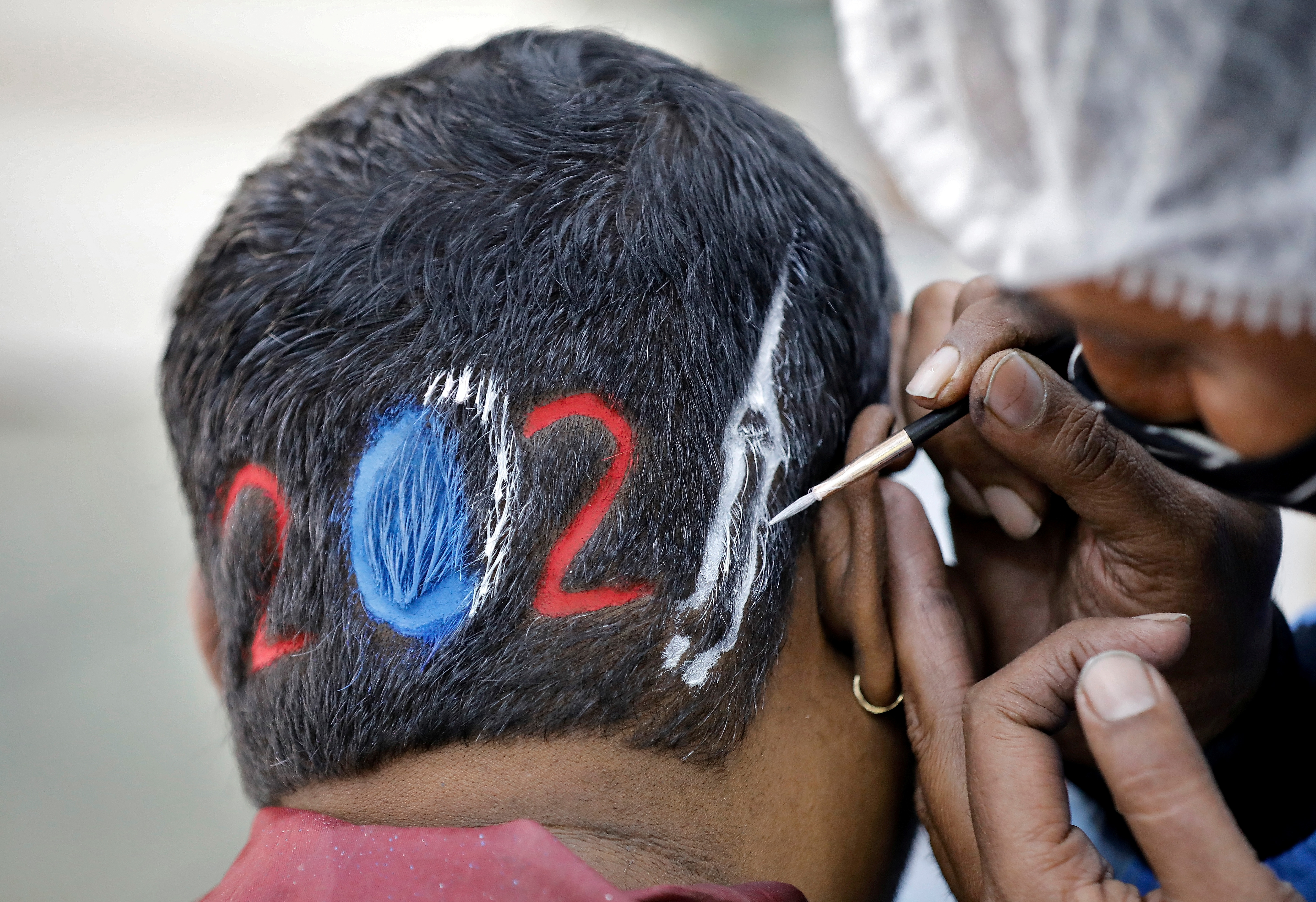 Un peluquero diseña un corte para un cliente que espera con ansias la llegada del 2021 en Ahmedabad, India (Reuters/ Amit Dave)