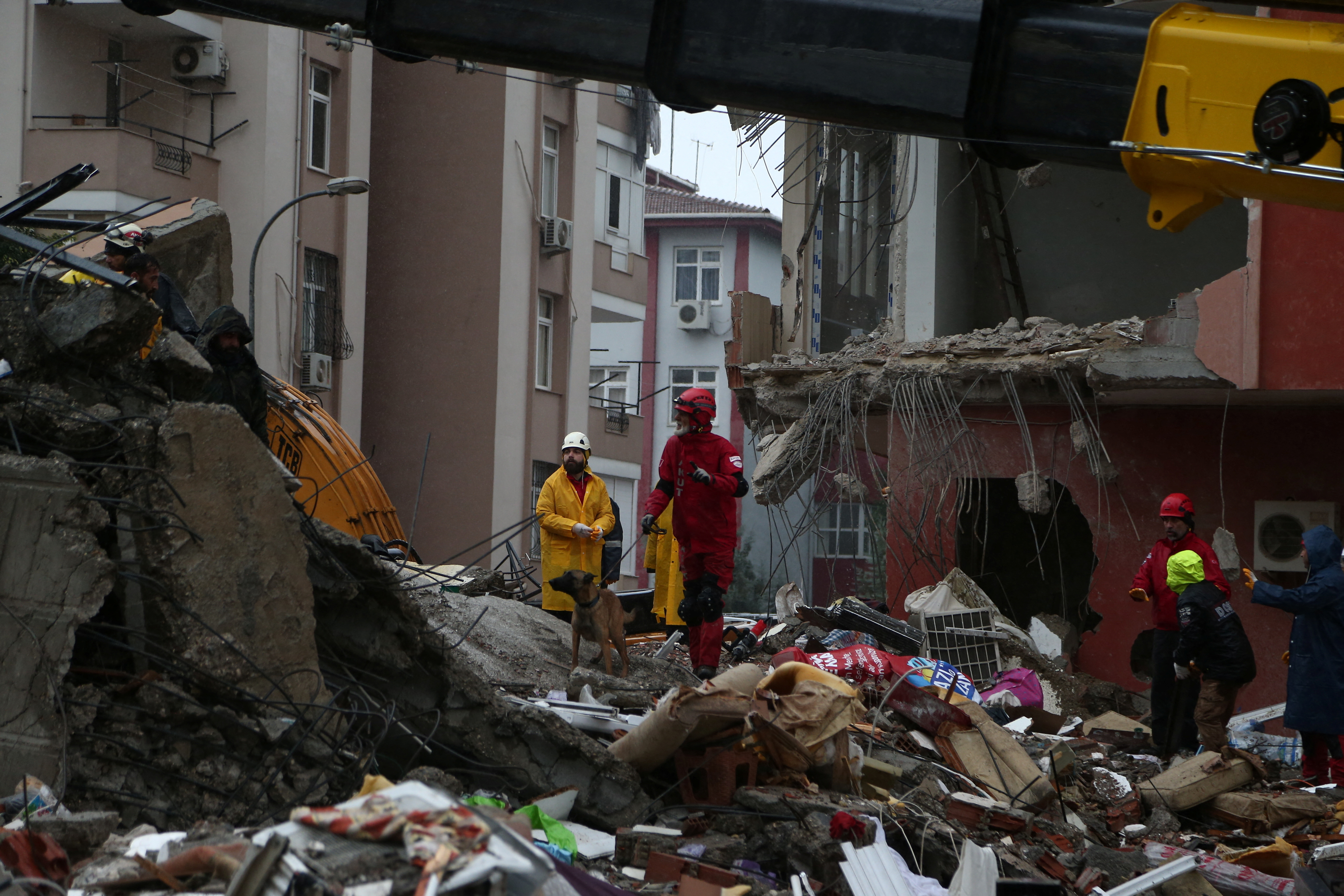 Un miembro de la Asociación de Búsqueda y Rescate (AKUT) con un perro rastreador busca sobrevivientes en el sitio de un edificio derrumbado luego de un terremoto en Adana, Turquía.
