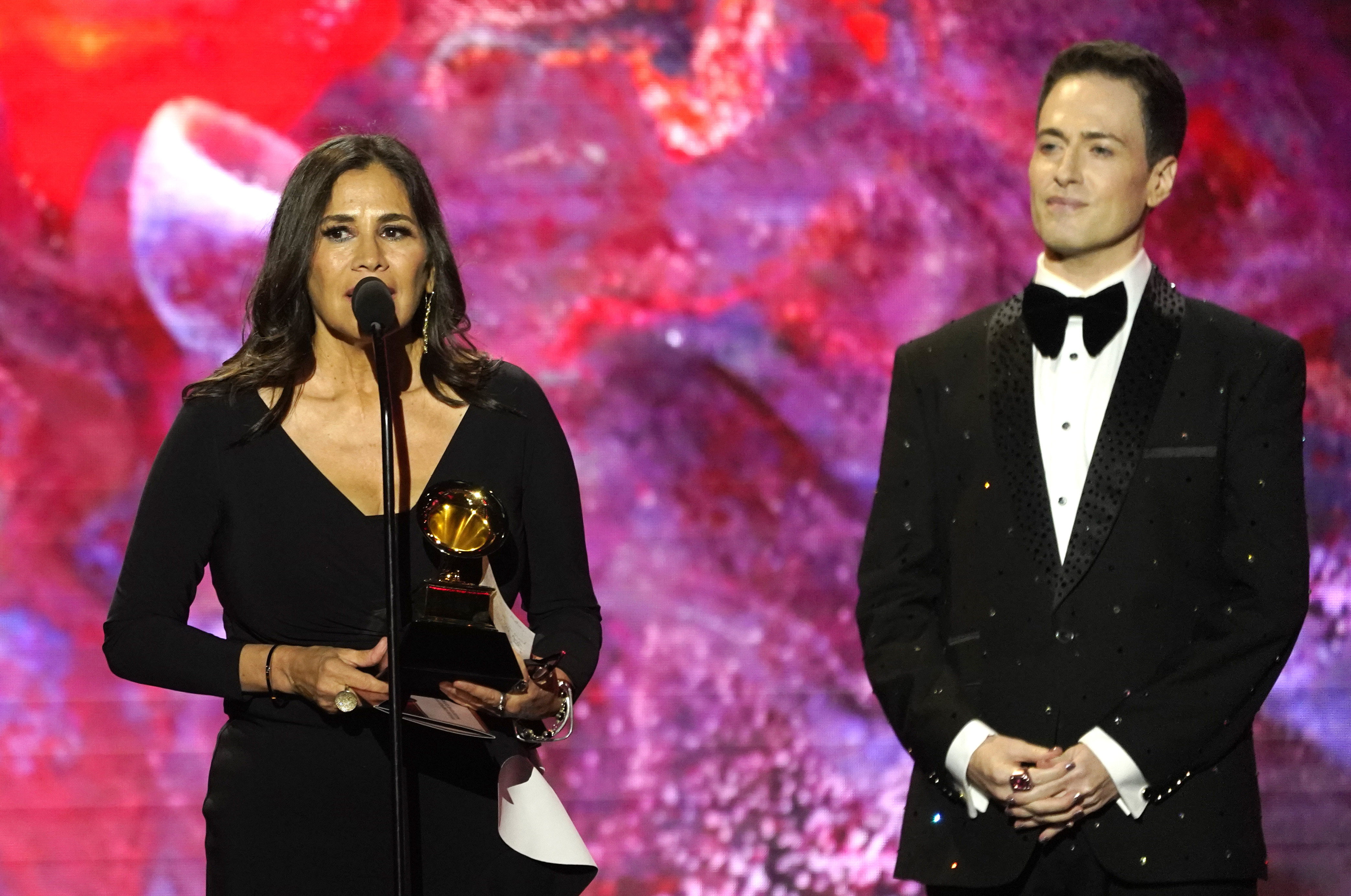 Germaine Franco, izquierda, recibe el premio a mejor banda sonora para un medio audiovisual por "Encanto" en la 65a entrega anual del Grammy el domingo 5 de febrero de 2023, en Los Angeles. A la derecha se encuentra el maestro de ceremonias Randy Rainbow. (Foto AP/Chris Pizzello)