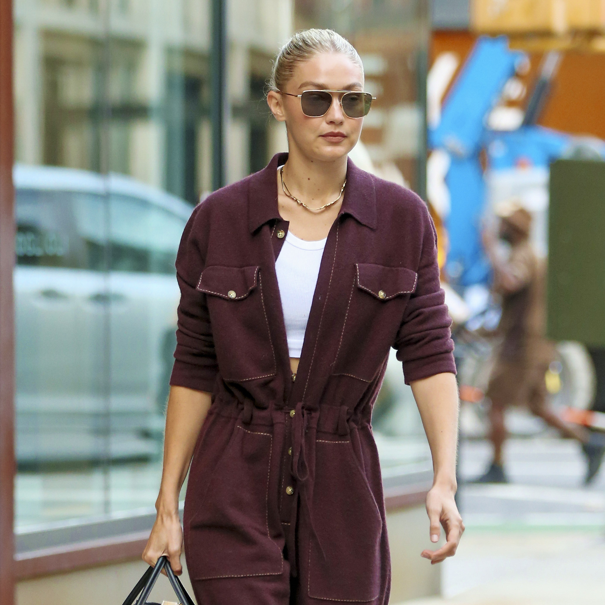 Heading to New York Airport, Gigi Hadid wore a burgundy romper that was unbuttoned to reveal a white top.