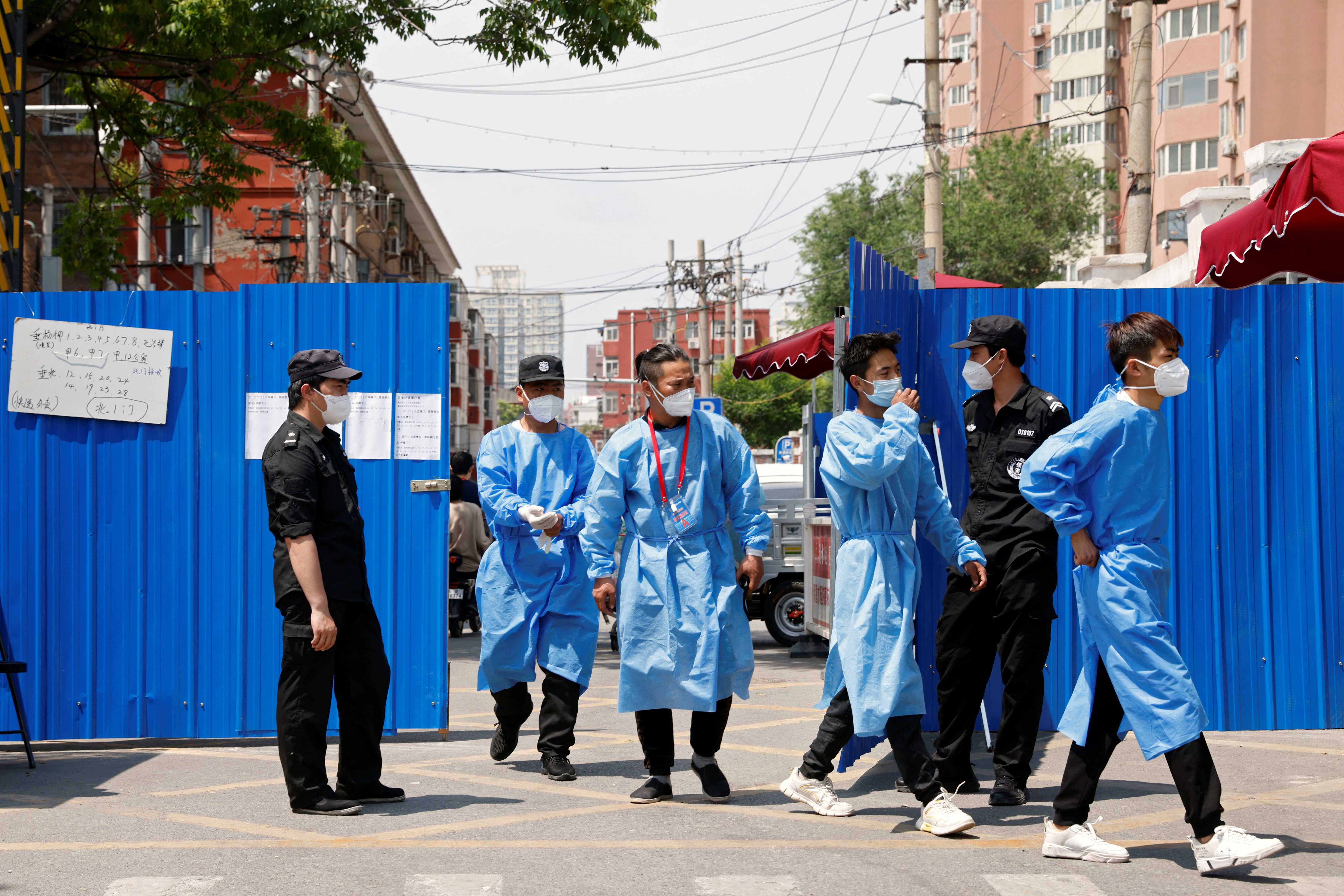 Workers in protective suits walk through the gate of a barricaded residential area under lockdown, amid the coronavirus disease (COVID-19) outbreak in Beijing, China May 17, 2022. REUTERS/Carlos Garcia Rawlins