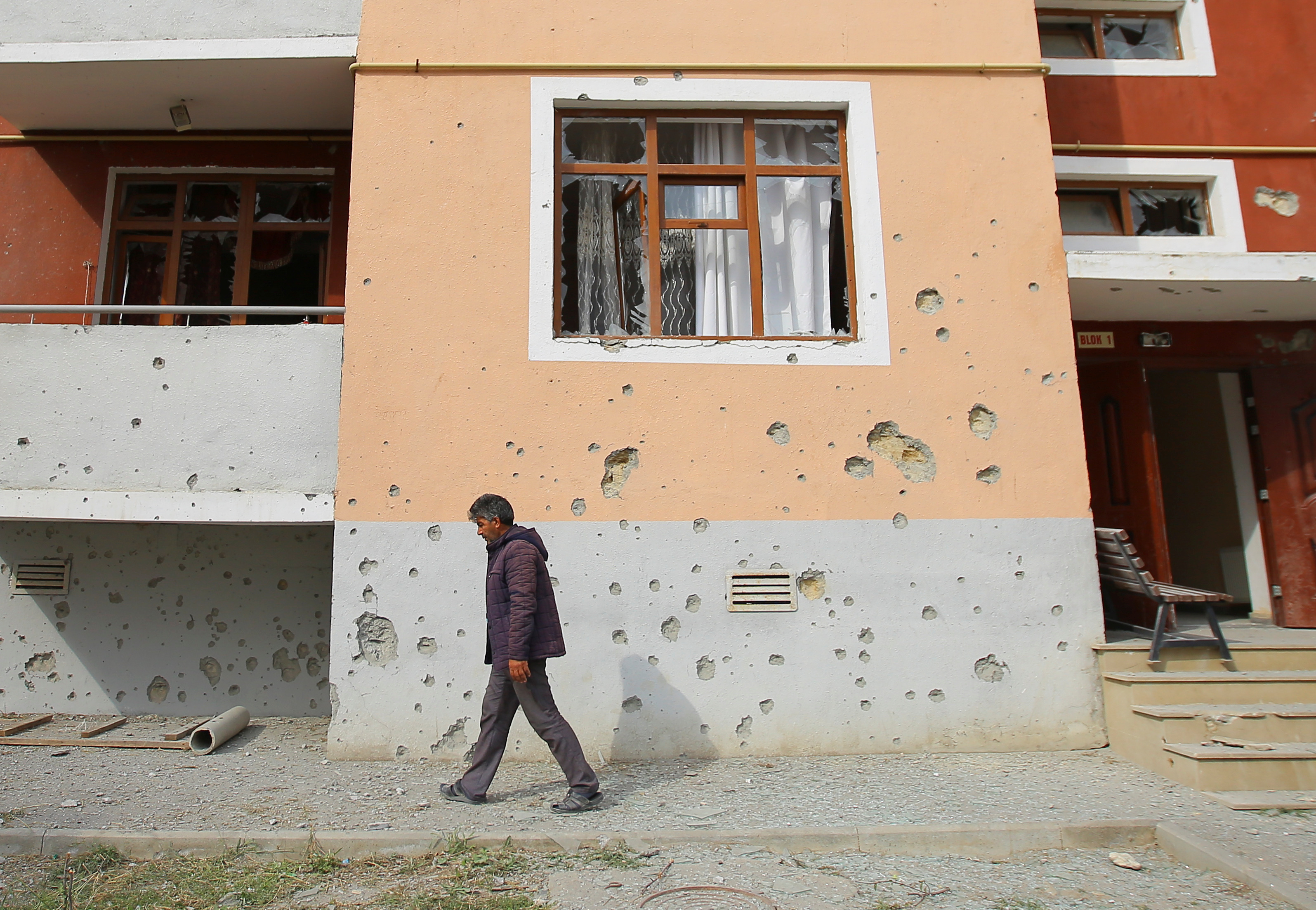 Un hombre camina junto a un edificio de apartamentos que presuntamente fue dañado por los recientes bombardeos durante los combates en la región separatista de Nagorno-Karabaj, en el distrito fronterizo de Tartar en Azerbaiyán. REUTERS/Aziz Karimov