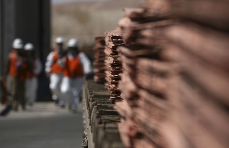 En primer plano, catodos de cobre, y más atrás mineros en la mina de Cobre Escondida, en Chile, la más grande del mundo