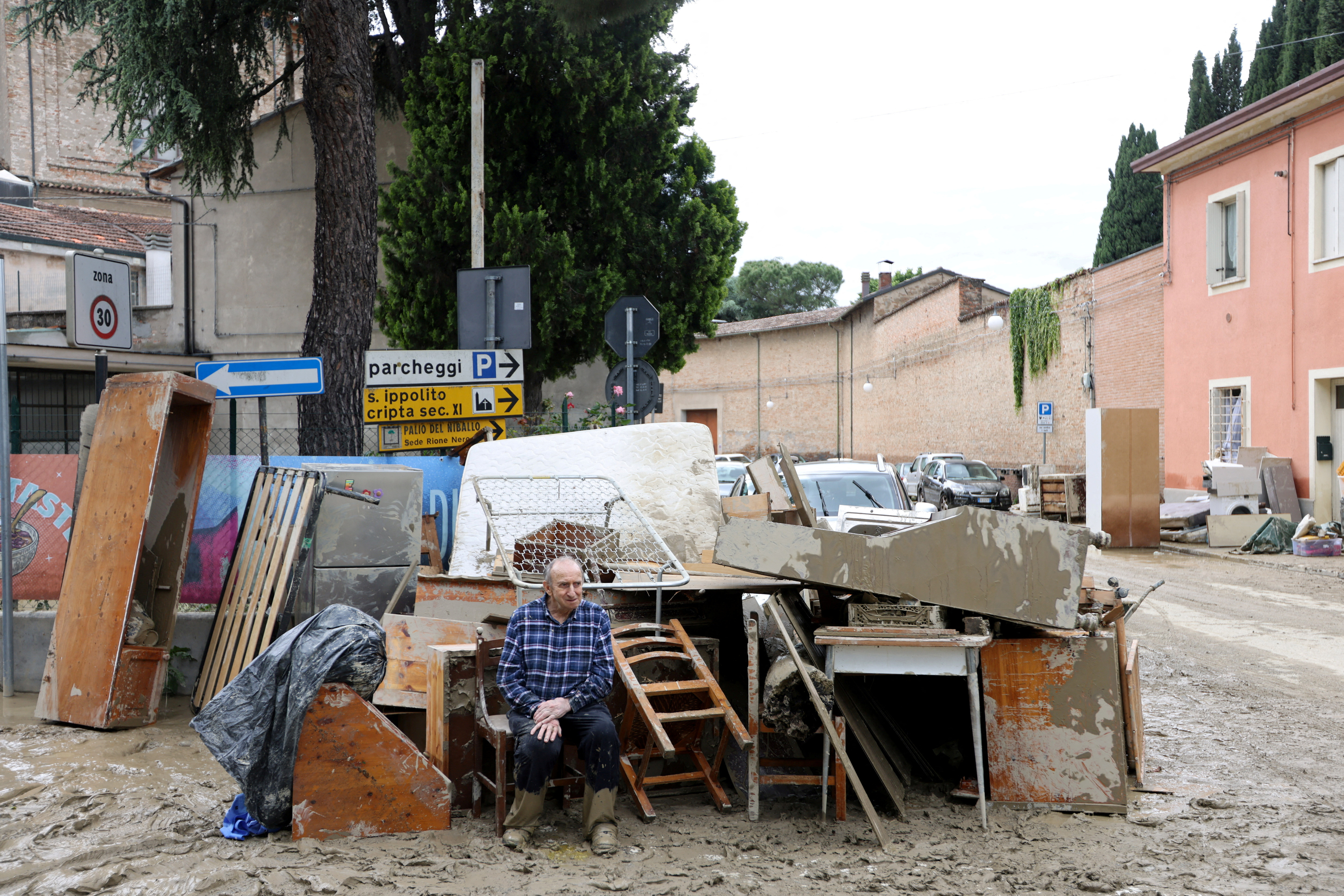 Un hombre sentado junto a sus pertenencias tras la inundación en Faenza, Italia, el 18 de mayo de 2023 (REUTERS/Claudia Greco)