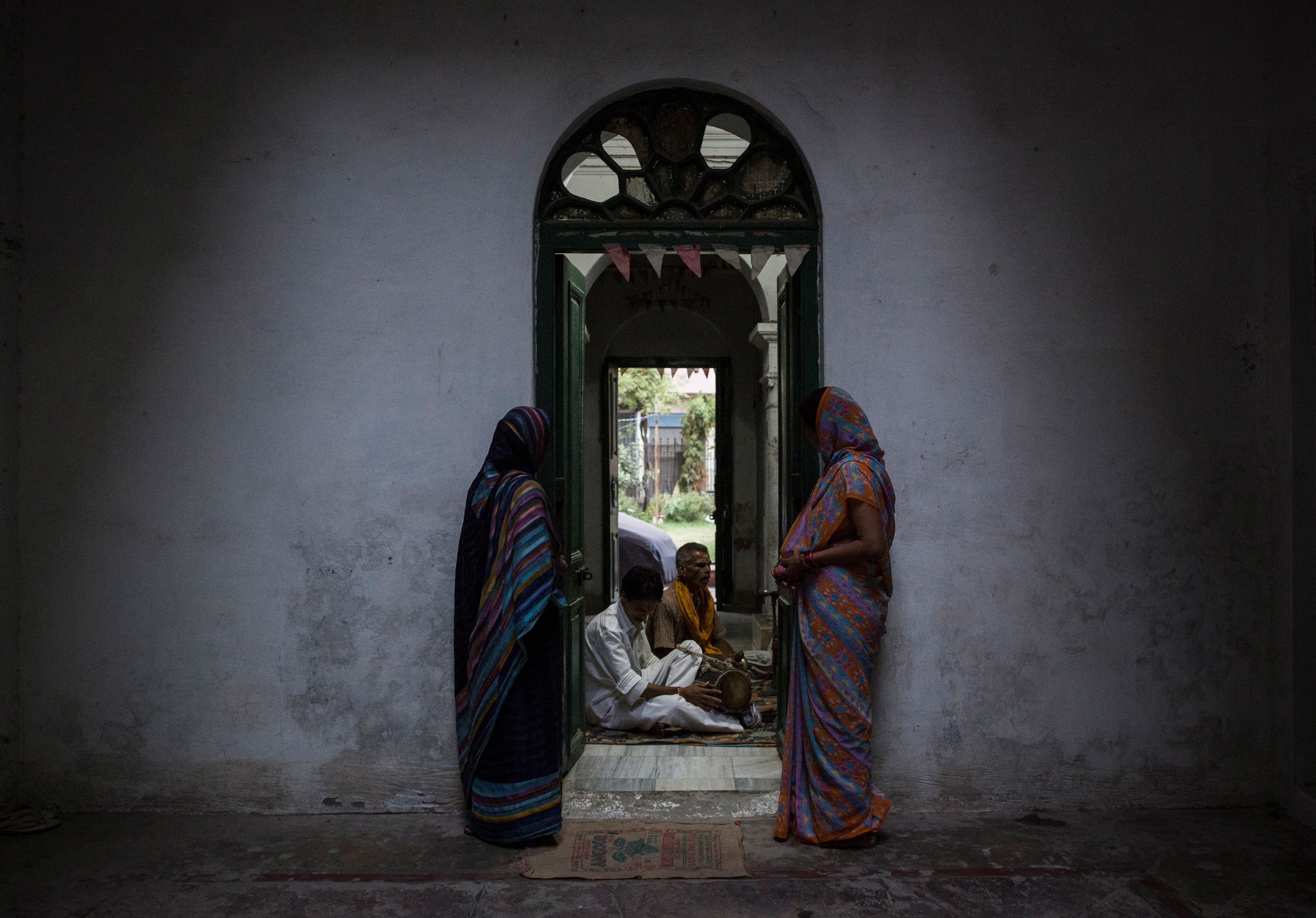 Familiares de mecenas escuchan a los sacerdotes mientras cantan durante las oraciones vespertinas en la Mukti Bhavan (Casa de la Salvación) en Varanasi, en el estado de Uttar Pradesh, al norte de la India, el 17 de junio de 2014.