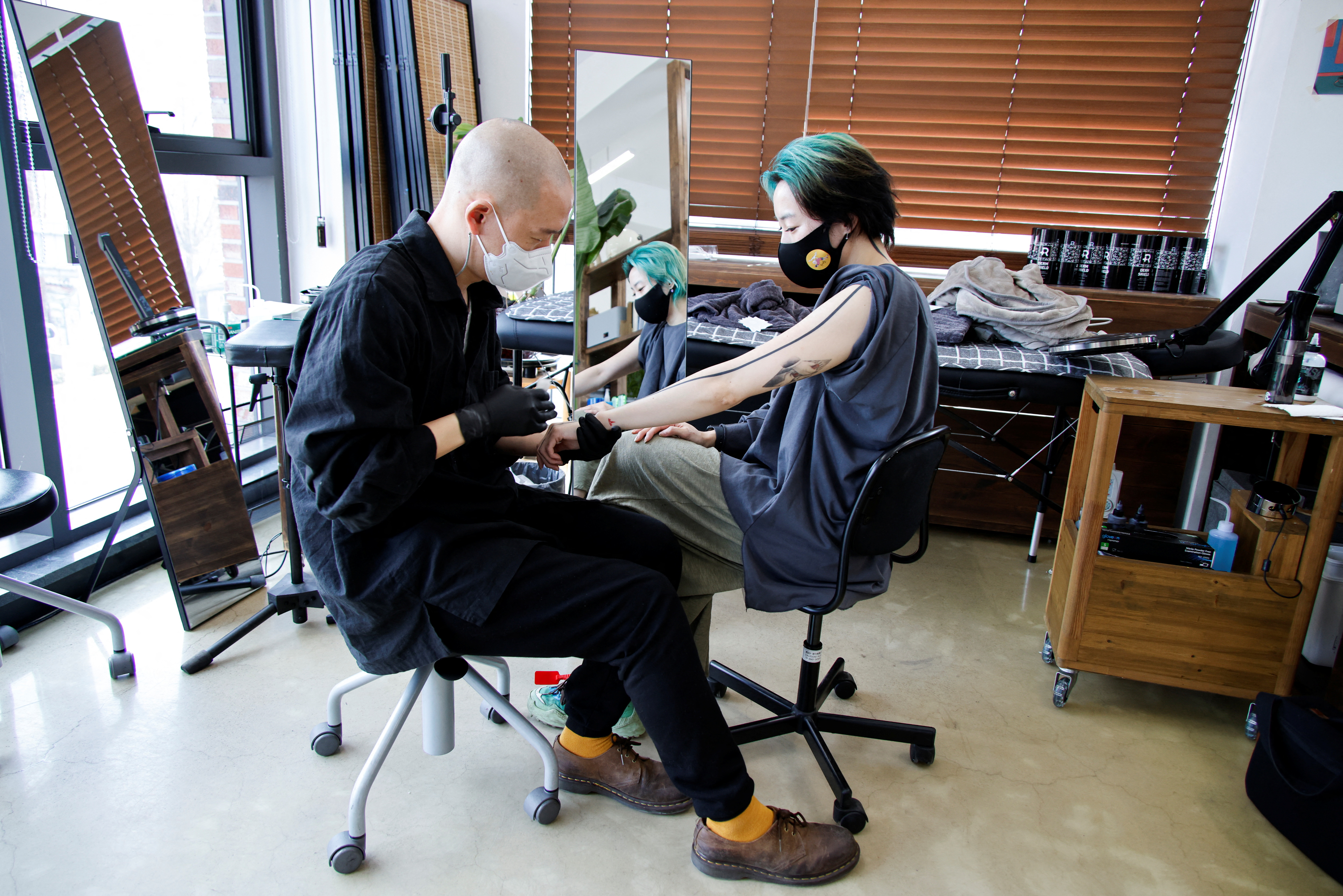 El tatuador Kim Do-yoon atiende a un cliente en su estudio de tatuajes en Seúl, Corea del Sur (REUTERS/ Heo Ran)