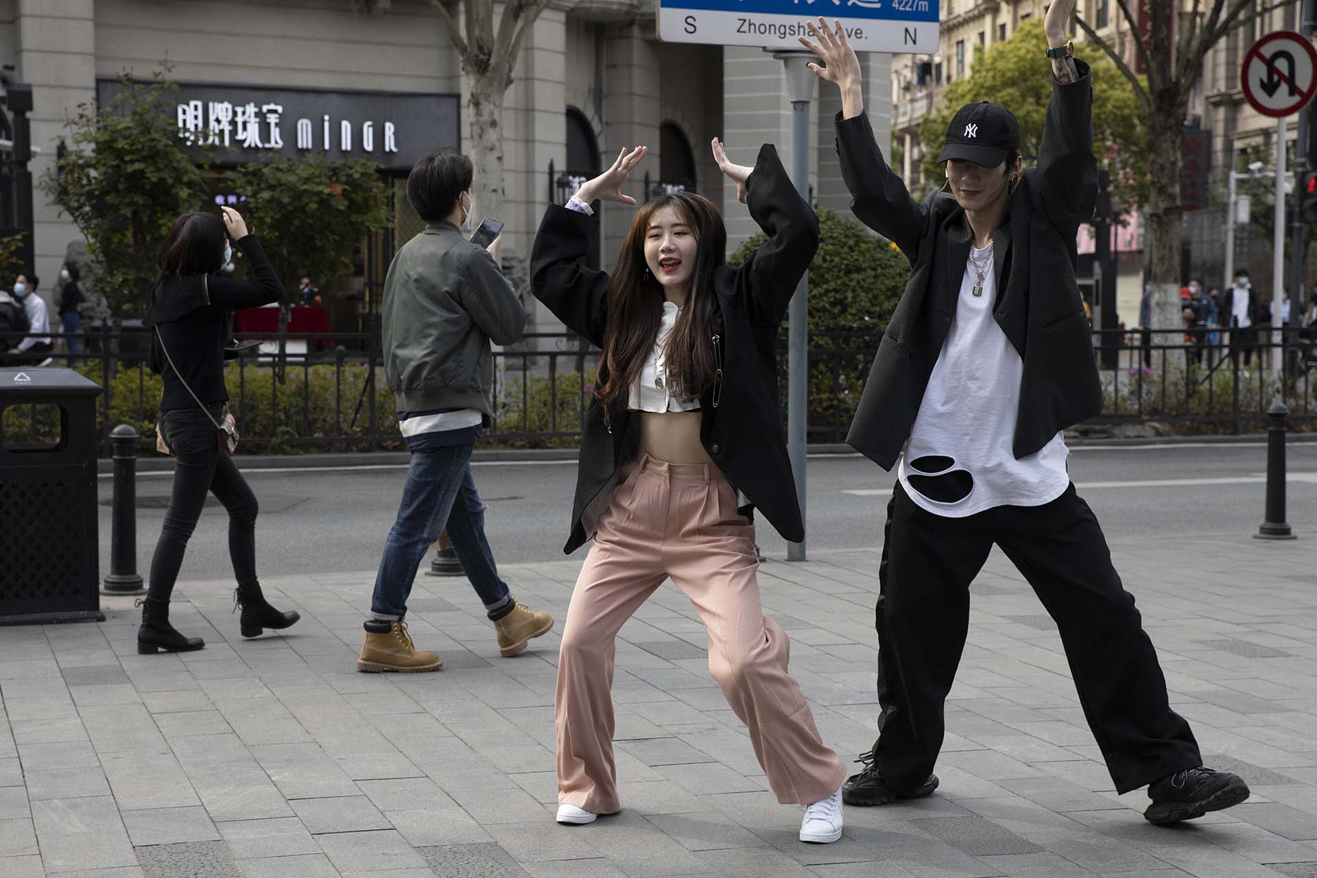 Una pareja de jóvenes se quitan sus máscaras faciales para grabar una coreografía en las calles de Wuhan, China (AP Photo/Ng Han Guan)