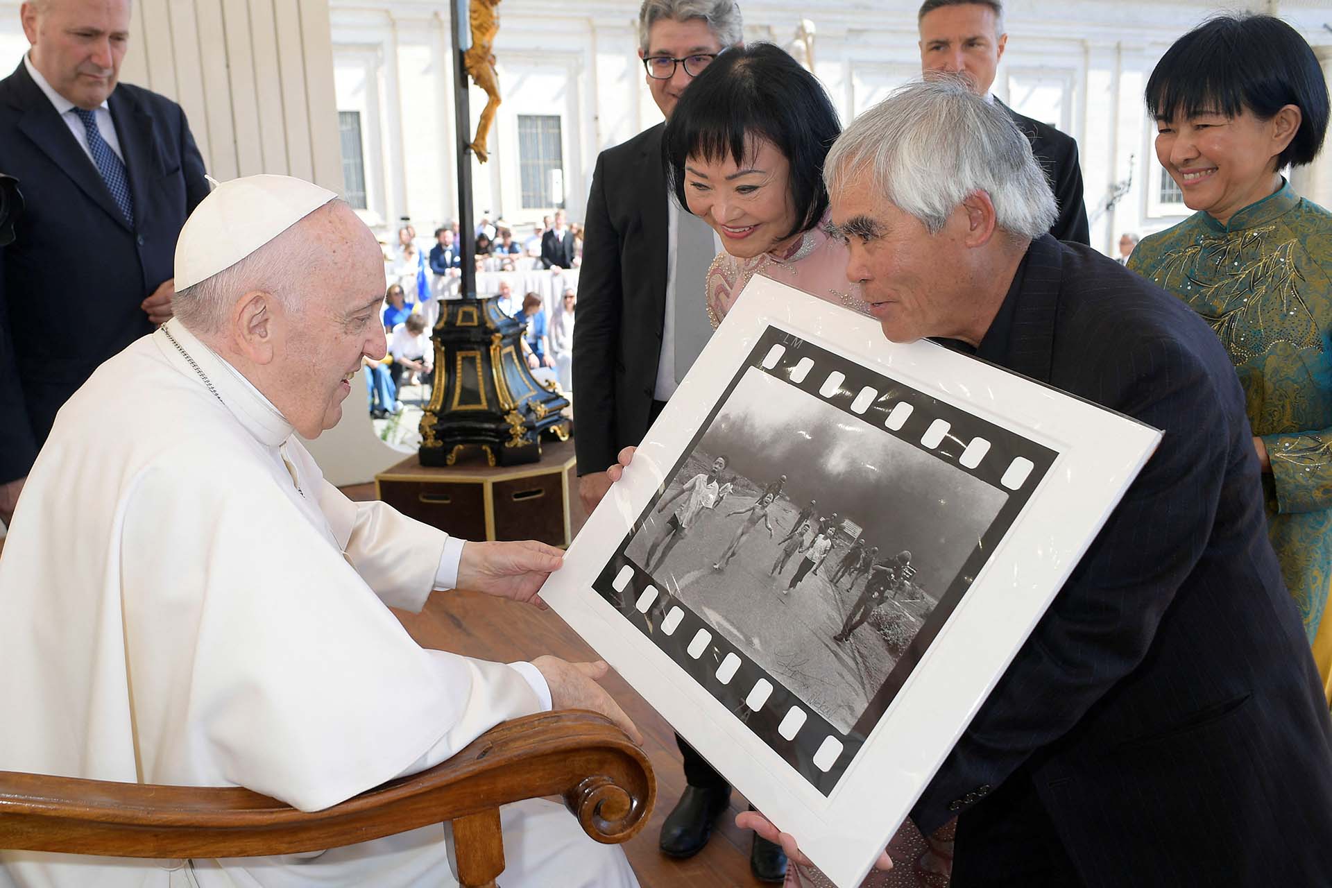 El fotógrafo Nick Ut le muestra al Papa Francisco su foto de 1972 "El terror de la guerra", también conocida como la "Niña del napalm", junto a Kim Phuc, el11 de mayo de 2022 (Medios del Vaticano/Folleto vía REUTERS)
