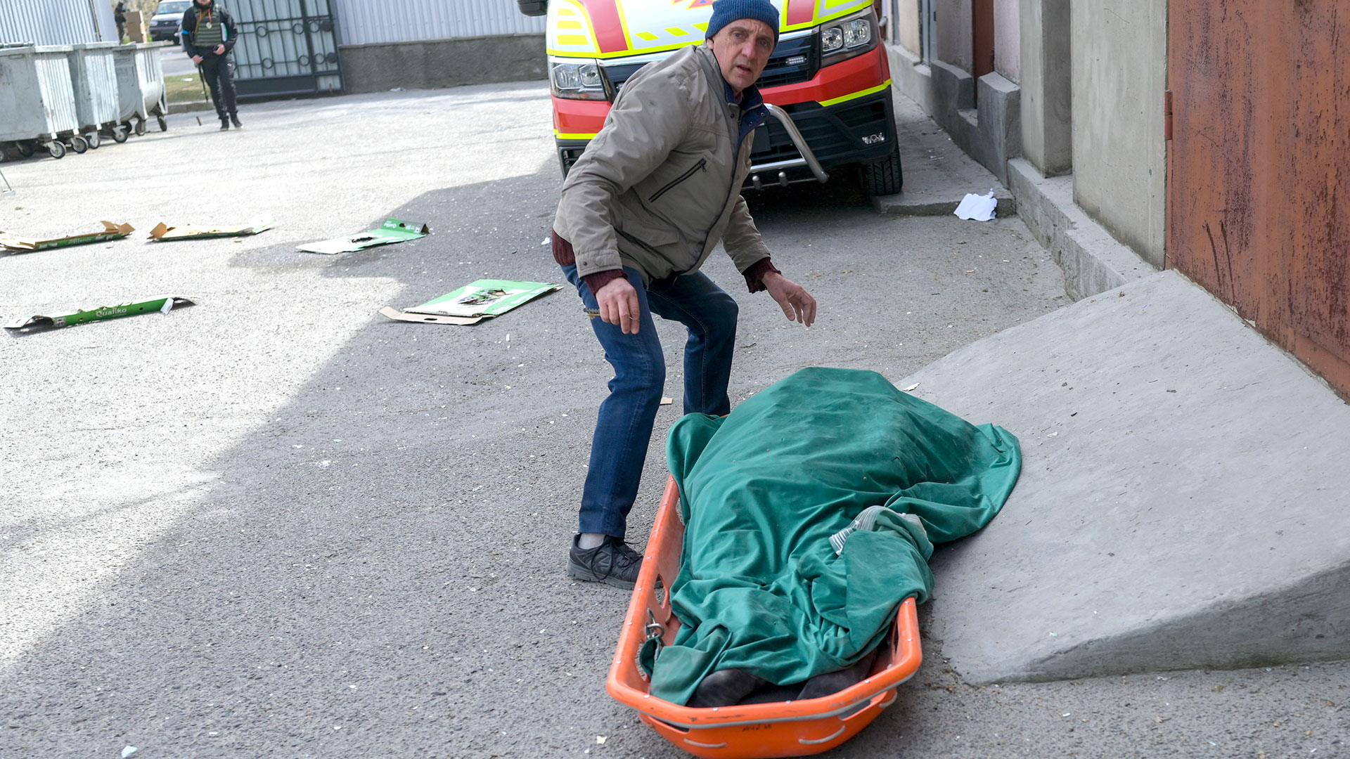 Un residente revisa el cadáver de una anciana cerca del edificio del gobierno alcanzado por cohetes rusos en Mykolaiv (AFP)
