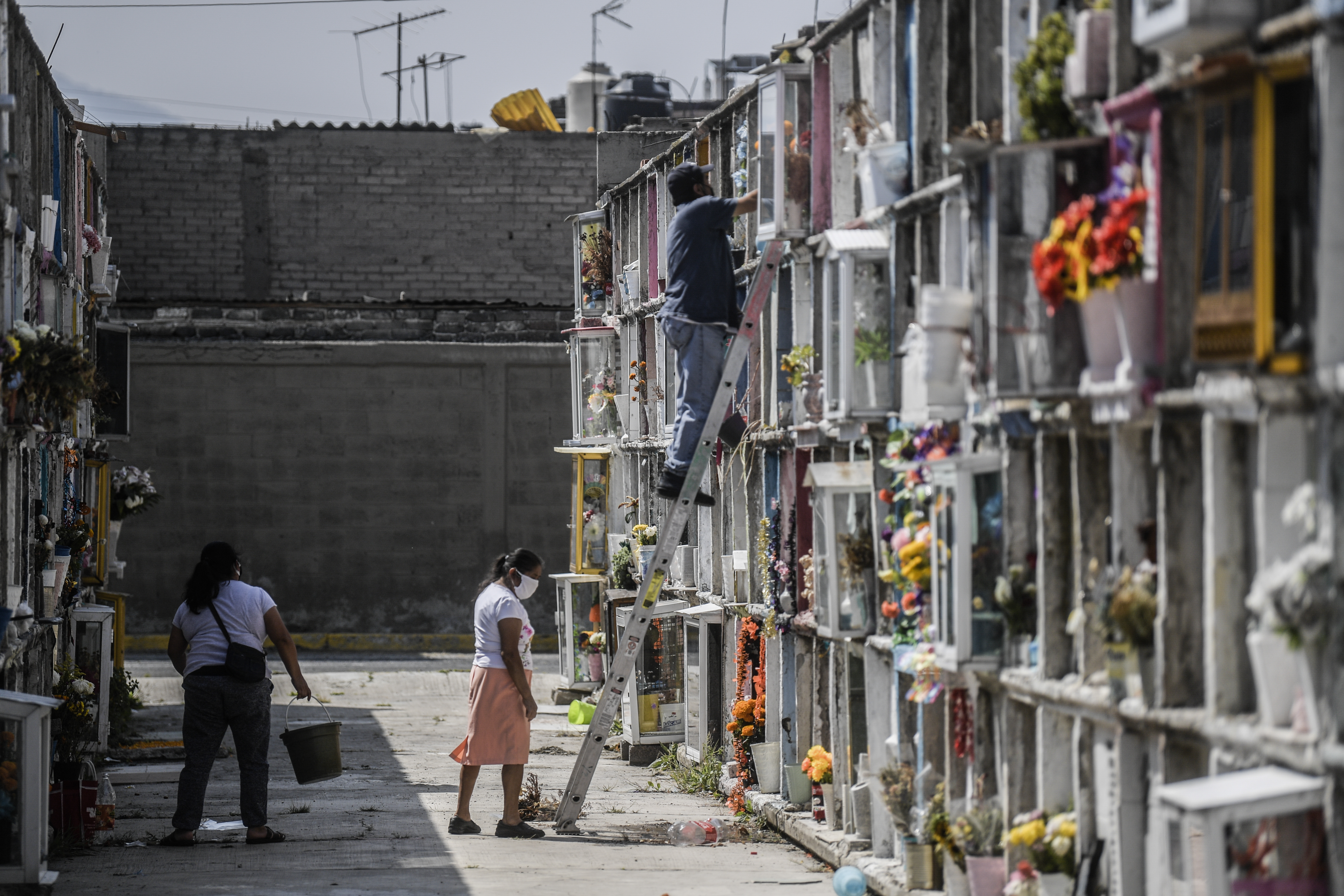 Personas decoran la tumba de un familiar antes del Día de Muertos en el panteón municipal de Nezahualcóyotl, México, el 28 de octubre de 2020, en medio de la pandemia del coronavirus COVID-19.