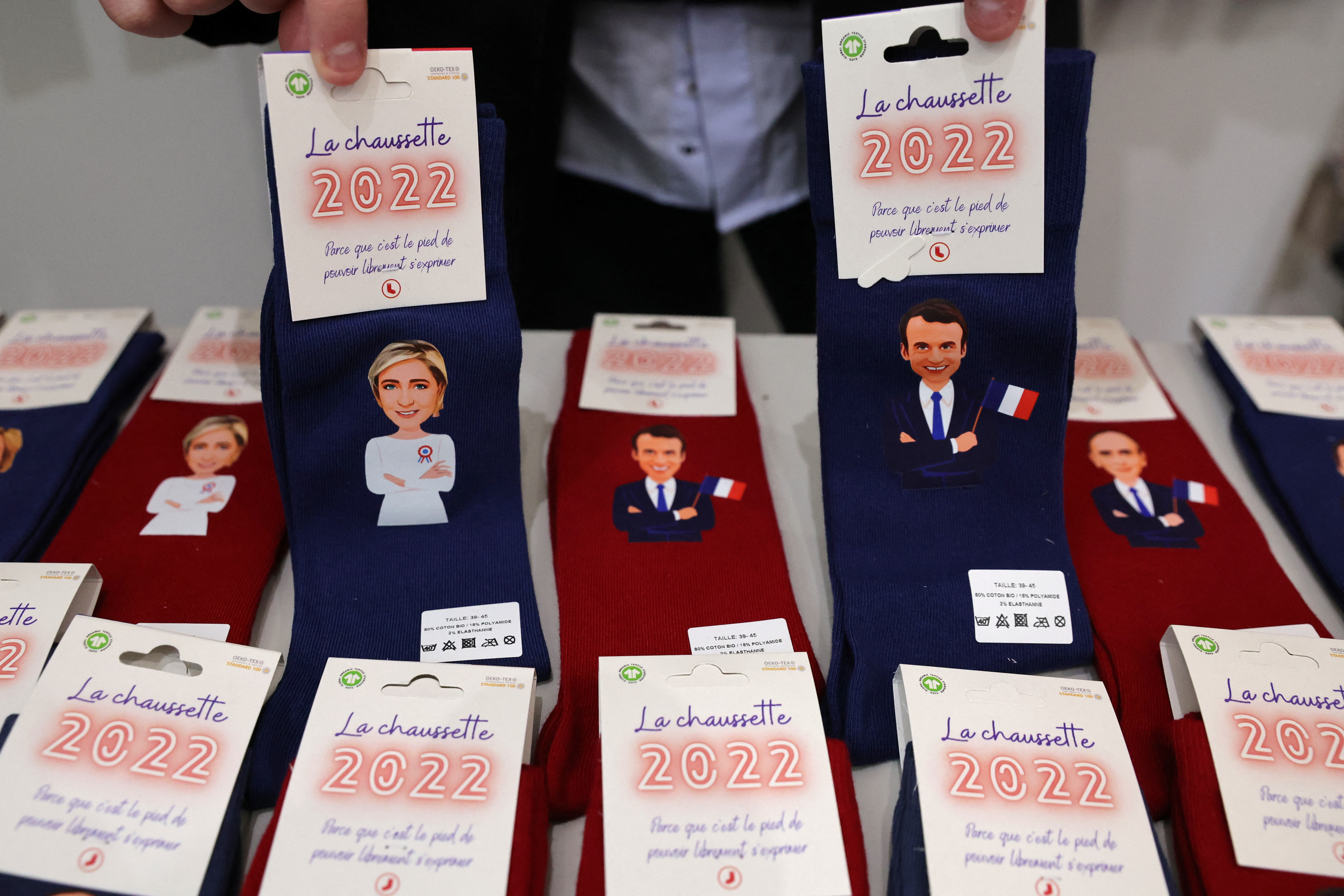 Maxime Lemersre, propietario de la tienda Chaussettes and compagnie, muestra calcetines decorados con las caras de Marine Le Pen, líder del partido francés de extrema derecha Agrupación Nacional (Rassemblement National) y candidata a las elecciones presidenciales francesas de 2022, y del presidente francés Emmanuel Macron, candidato a su reelección )REUTERS/Pascal Rossignol)