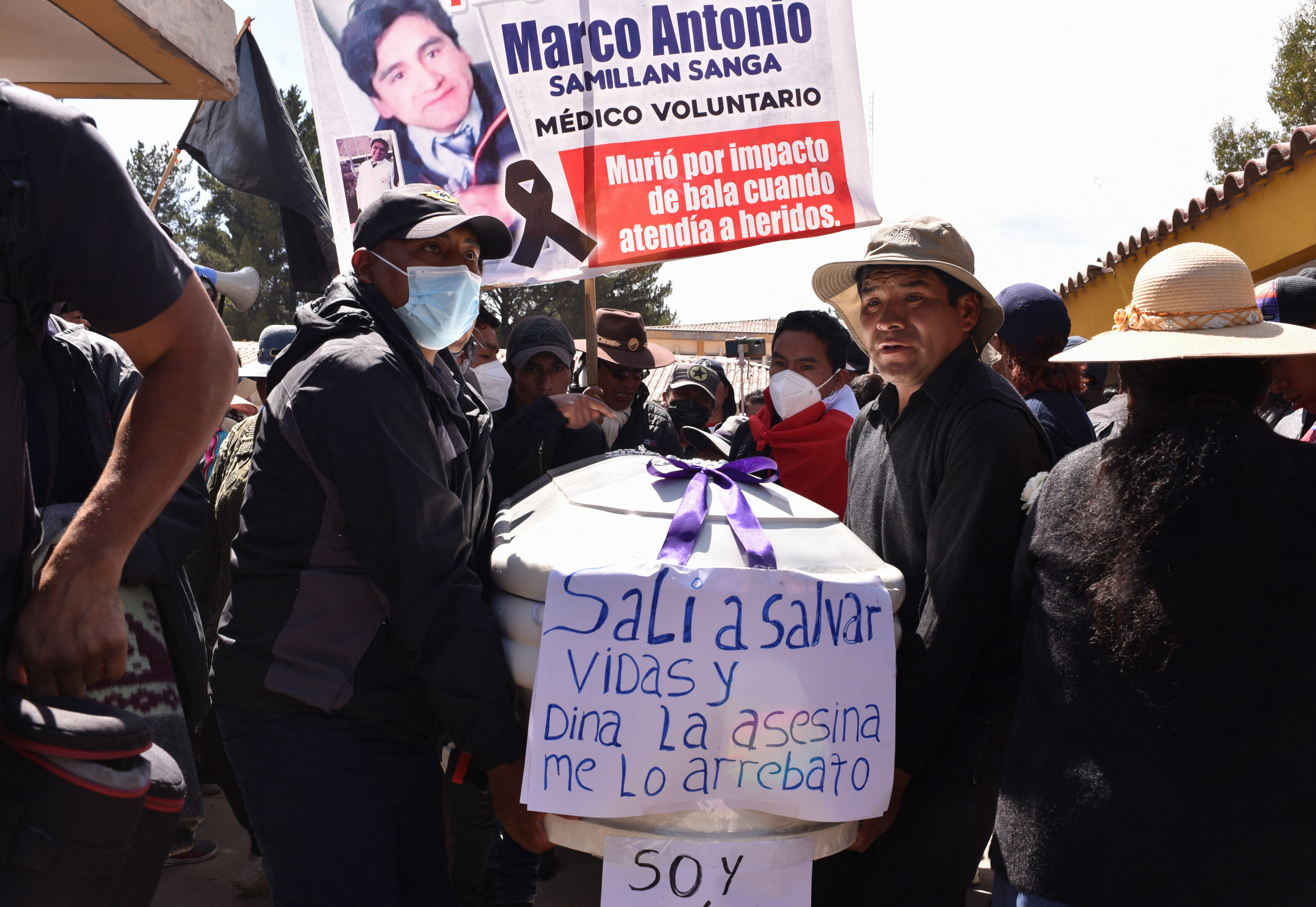 People carry the coffin of a man, who died in violent clashes earlier this week, ignited by the ouster of leftist President Pedro Castillo, in Juliaca, Peru January 11, 2023. The signs read "Marco Antonio, a volunteer doctor, was shot dead while treating the wounded," and "I went out to save lives and Dina, the assassin, took mine”, referring to current Peruvian President Dina Boluarte.  REUTERS/Pedro Anza NO RESALES. NO ARCHIVES