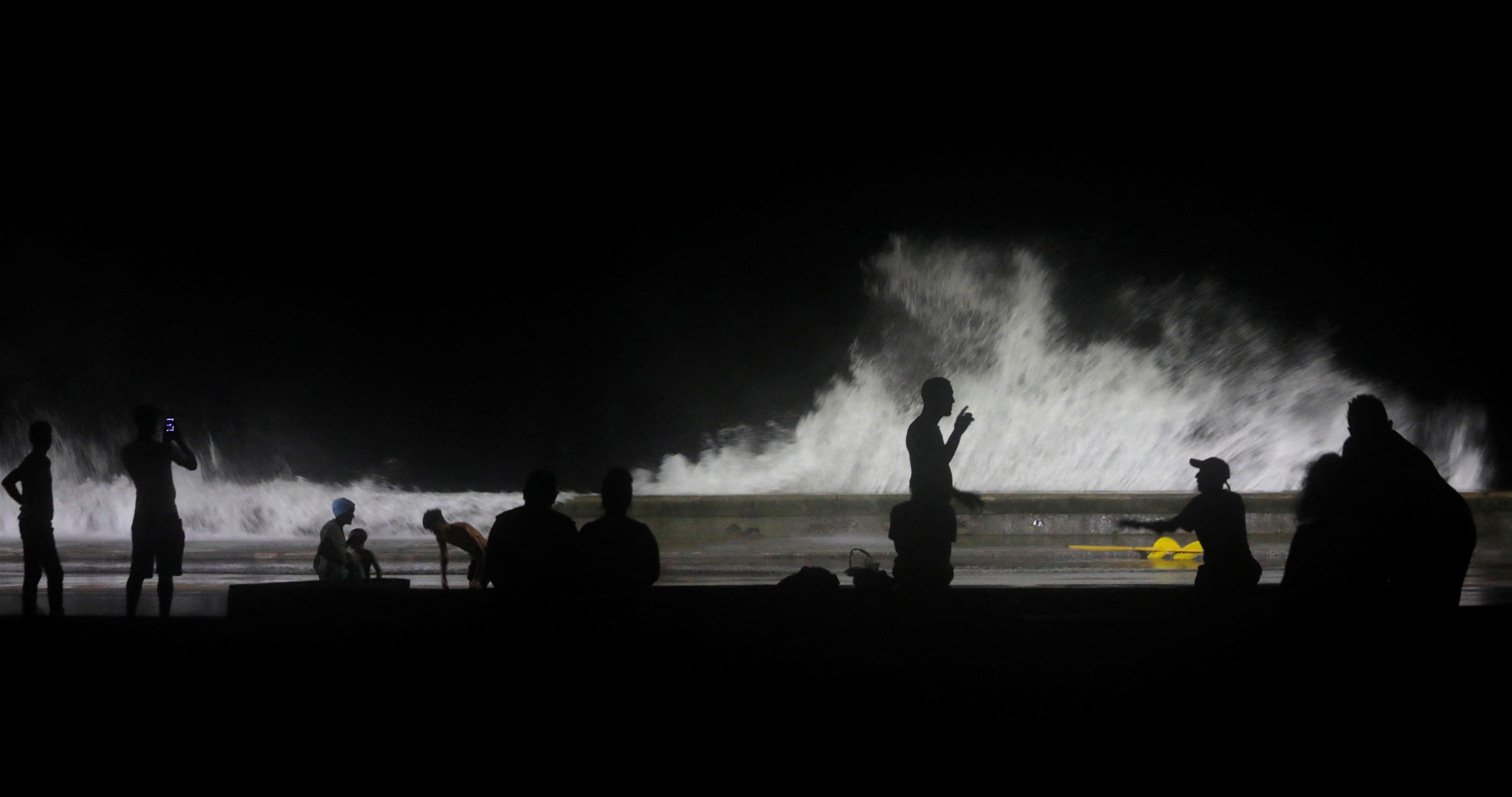 La gente observa las olas rompiendo en el paseo marítimo como consecuencia del huracán Ian en La Habana. 
