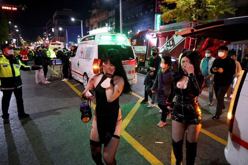 Partygoers walk past ambulances at the site where dozens of people were killed or injured in a stampede during a Halloween festival in Seoul, South Korea.  October 30, 2022. (Photo: REUTERS/Kim Hong-ji)