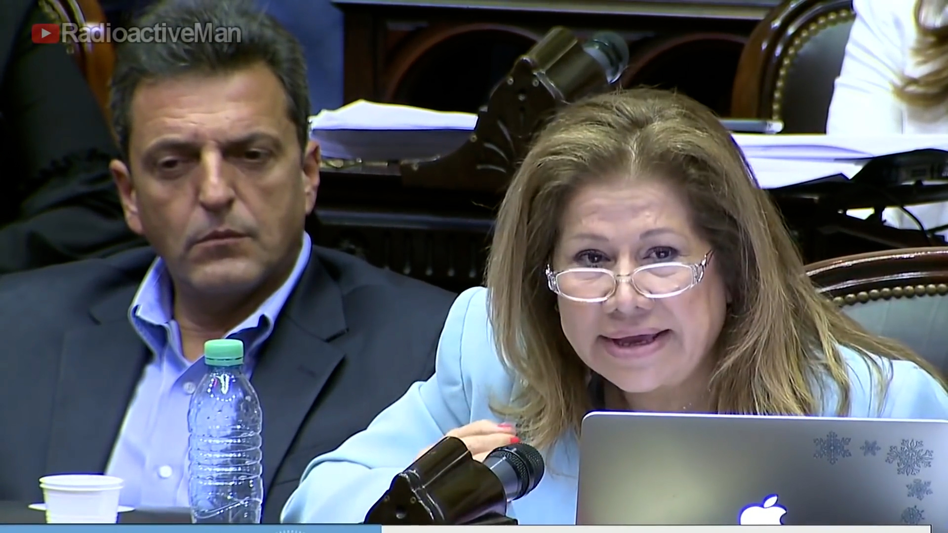 Sergio Massa ejerce una especia de poder mental sobre una botella de plástico, mientras la diputada Graciela Camaño expone en la Cámara de Diputados. 