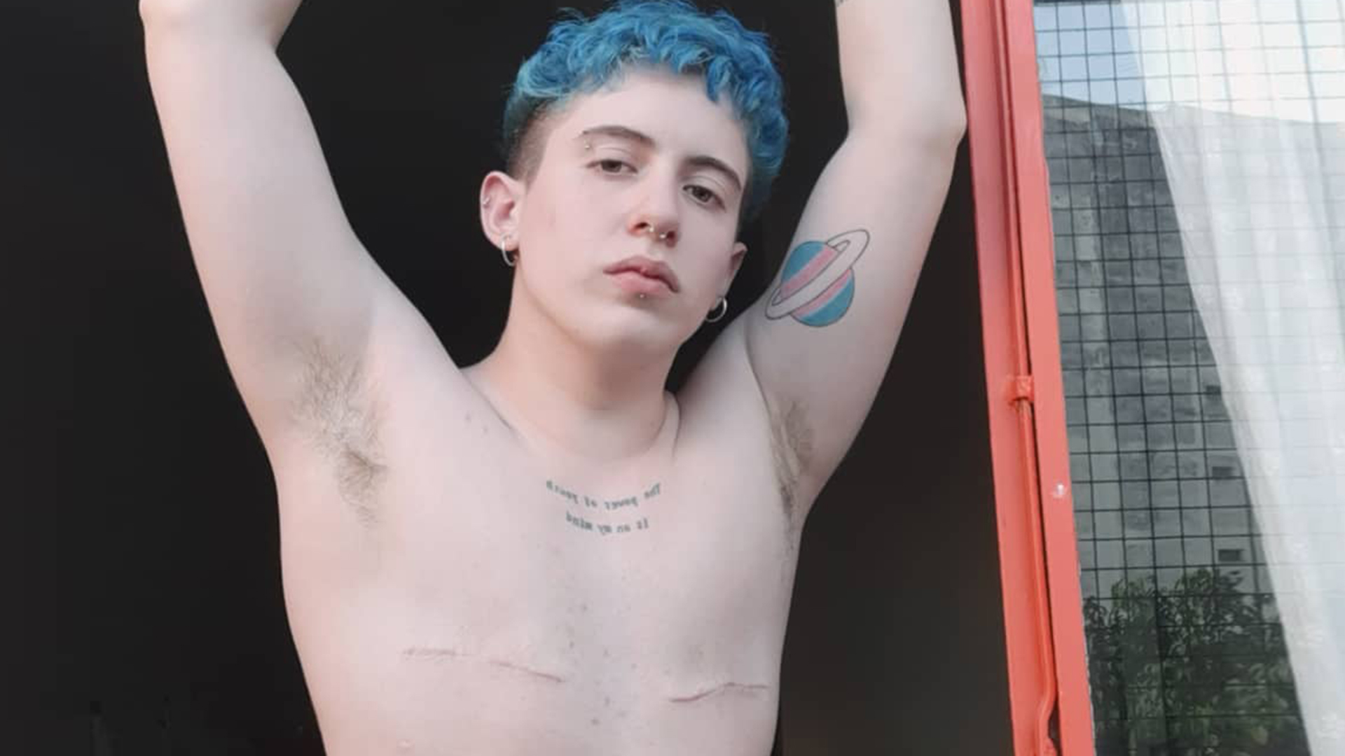 Enzo lleva un tatuaje con los colores de la bandera trans. En su pecho, las cicatrices de la mastectomía
