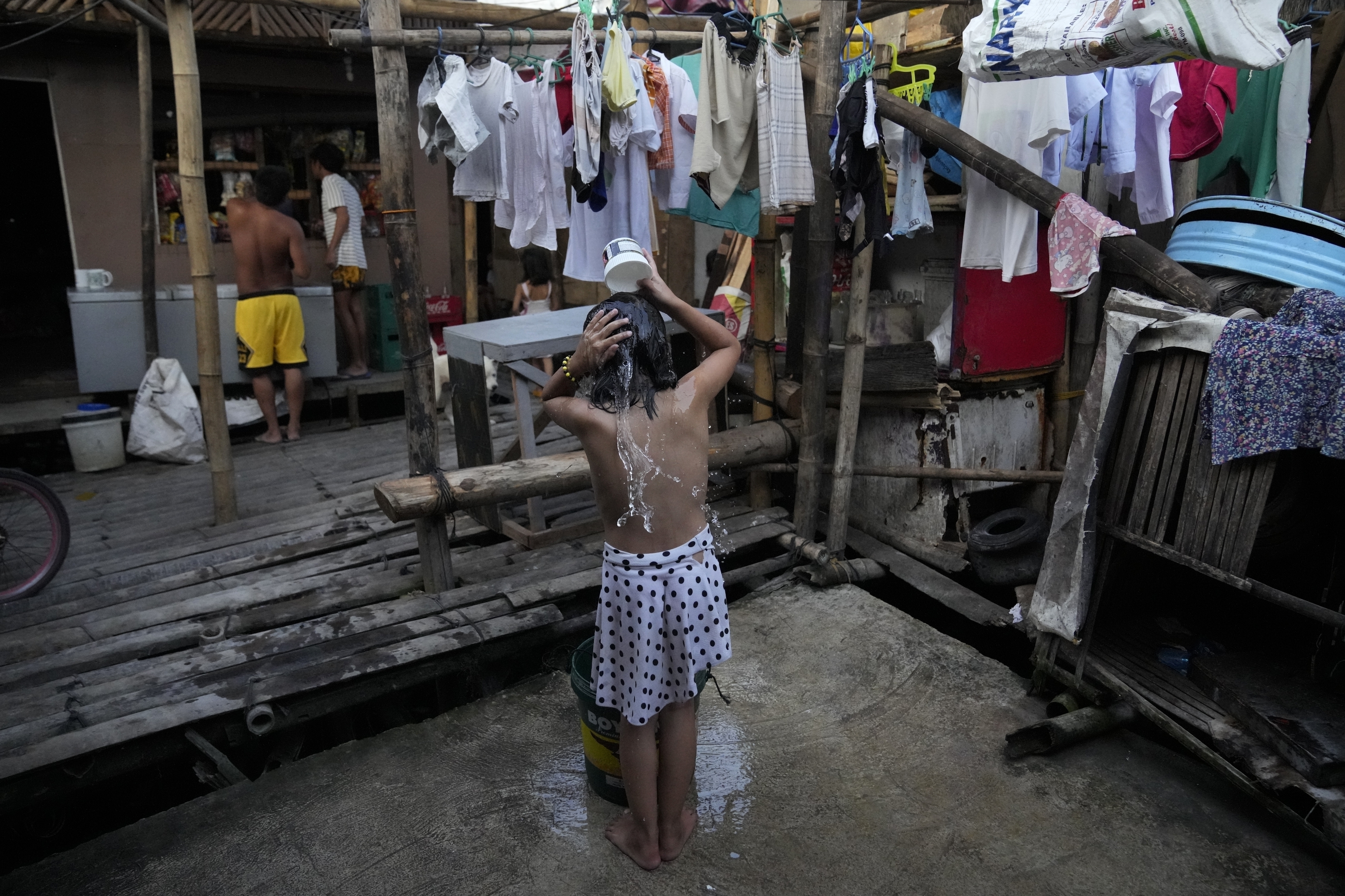 Una niña se baña cerca de una bomba de agua manual en una barriada en Muntinlupa, Filipinas, el 21 de marzo de 2023. (AP Foto/Aaron Favila)