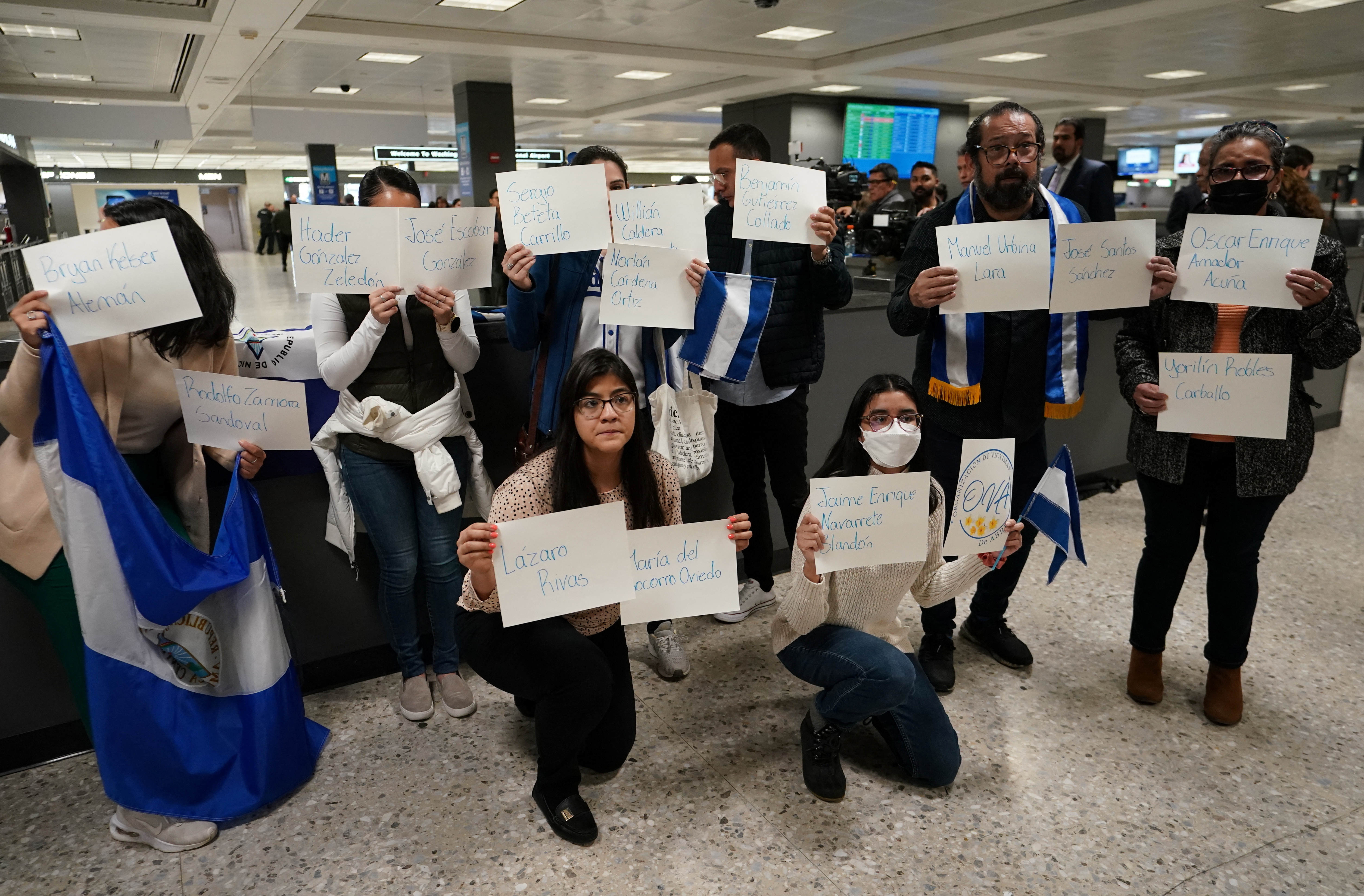Activists hold up signs with the names of some of the more than 200 political prisoners released from Nicaragua, as they await their arrival at Dulles International Airport in Virginia outside Washington, U.S., February 9, 2023. REUTERS/Kevin Lamarque