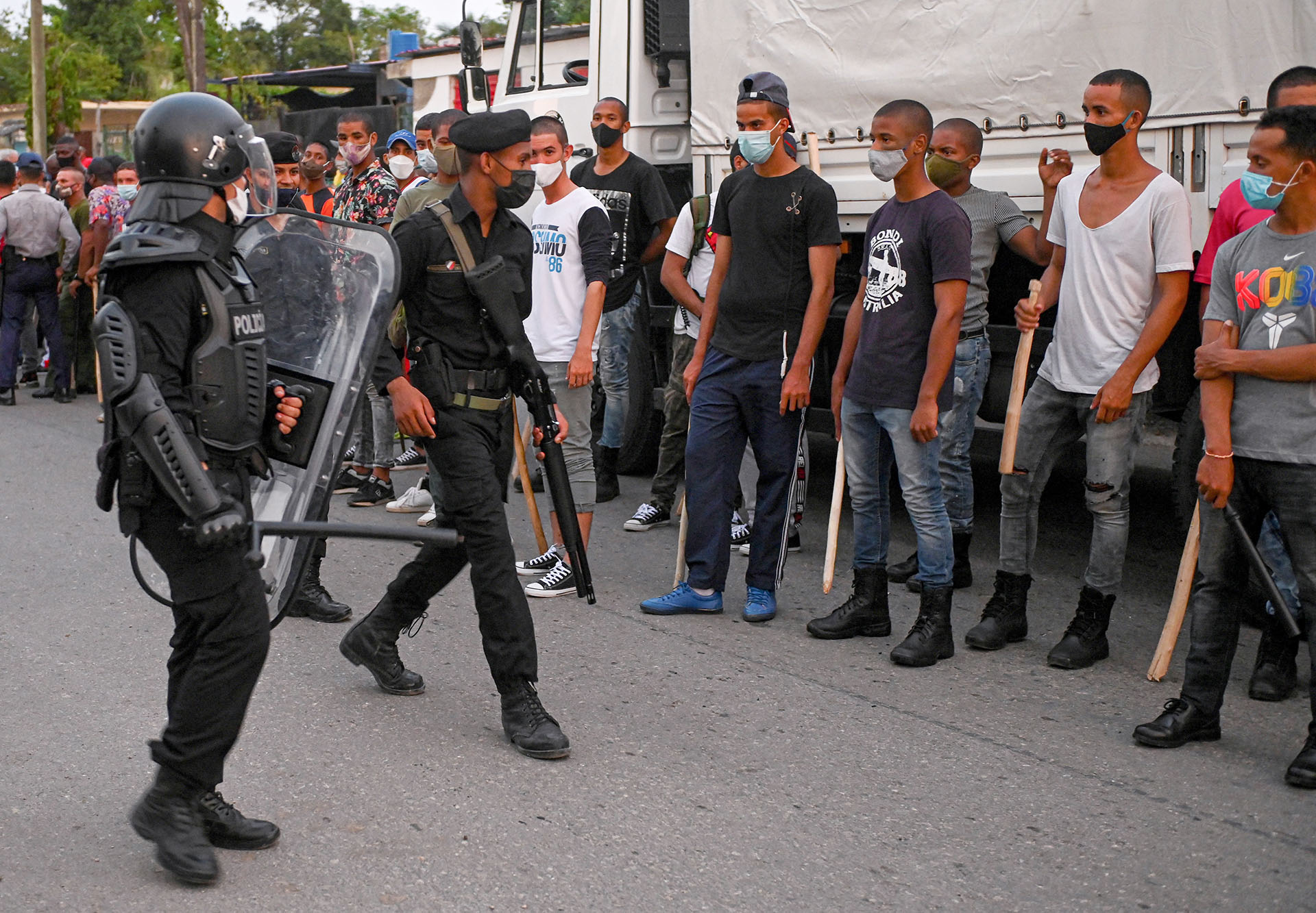 Jóvenes que apoyan al régimen castrista formados con palos frente a las fuerzas de seguridad en el municipio de Arroyo Naranjo, La Habana 