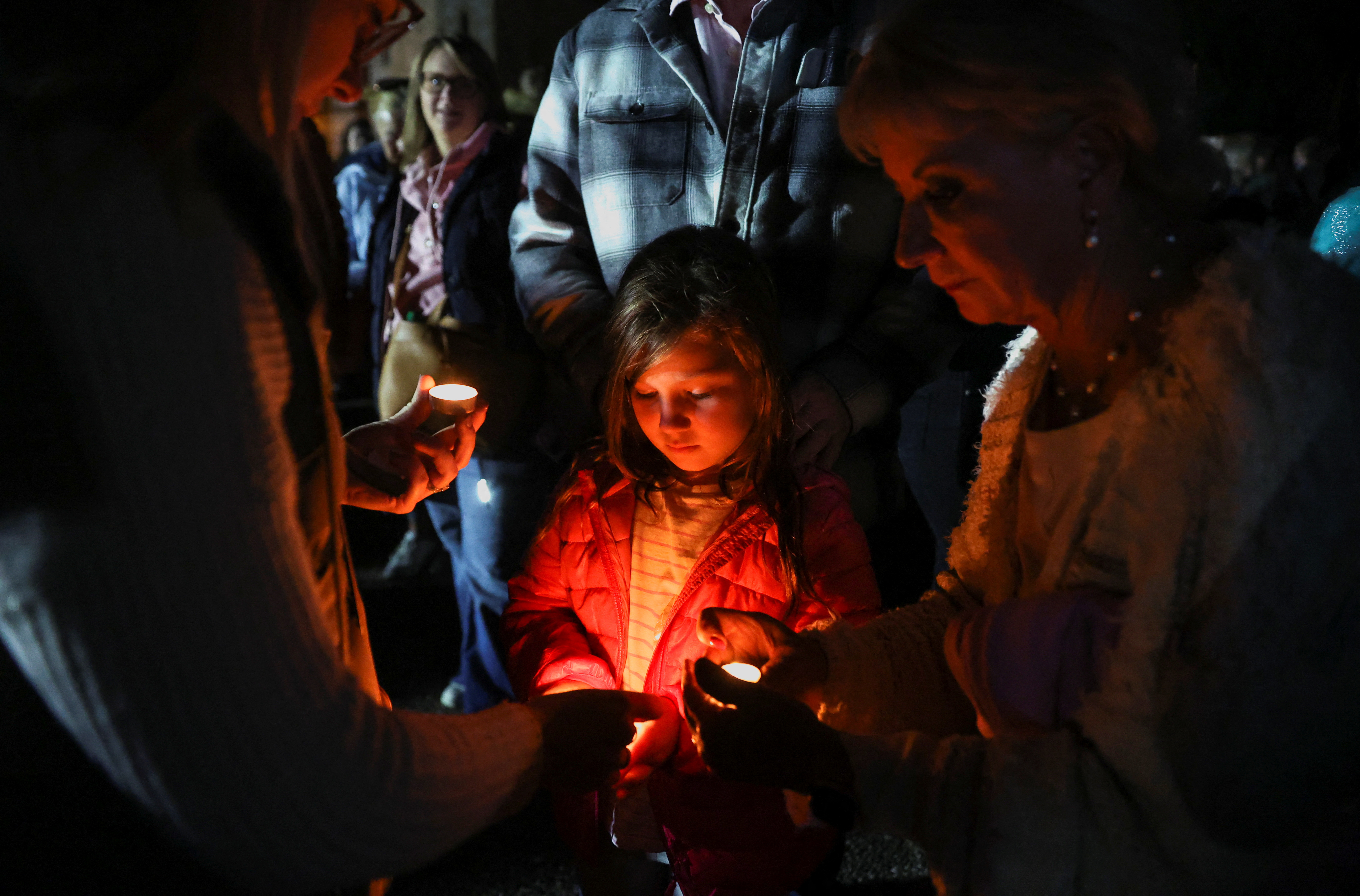 Una niña sostiene una vela mientras la gente asiste a un "momento nacional de reflexión" en honor a la difunta reina Isabel II, el día antes de su funeral, en Windsor, Gran Bretaña 18 de septiembre de 2022. REUTERS/Carl Recine