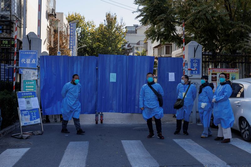 Trabajadores sanitarios frente a la entrada vallada de un complejo residencial que fue puesto bajo confinamiento mientras continúan los brotes de la enfermedad del coronavirus (COVID-19) en Beijing, 7 de noviembre de 2022. REUTERS/Thomas Peter