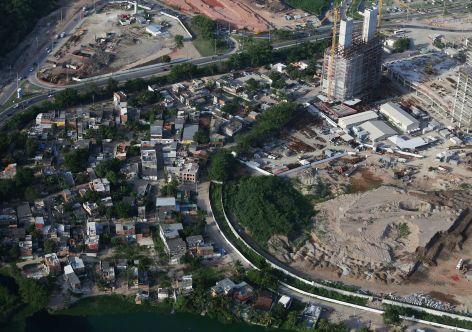 RIO DE JANEIRO, BRAZIL - FEBRUARY 24:  Construction continues (R) at the Olympic Park for the Rio 2016 Olympic Games in the Barra da Tijuca neighborhood, as remaining homes from the Vila Autodromo favela stand (L) on February 24, 2015 in Rio de Janeiro, Brazil. The Olympic Park will occupy 1.18 million square meters hosting 16 Olympic disciplines and will be the heart of the games.  (Photo by Mario Tama/Getty Images)