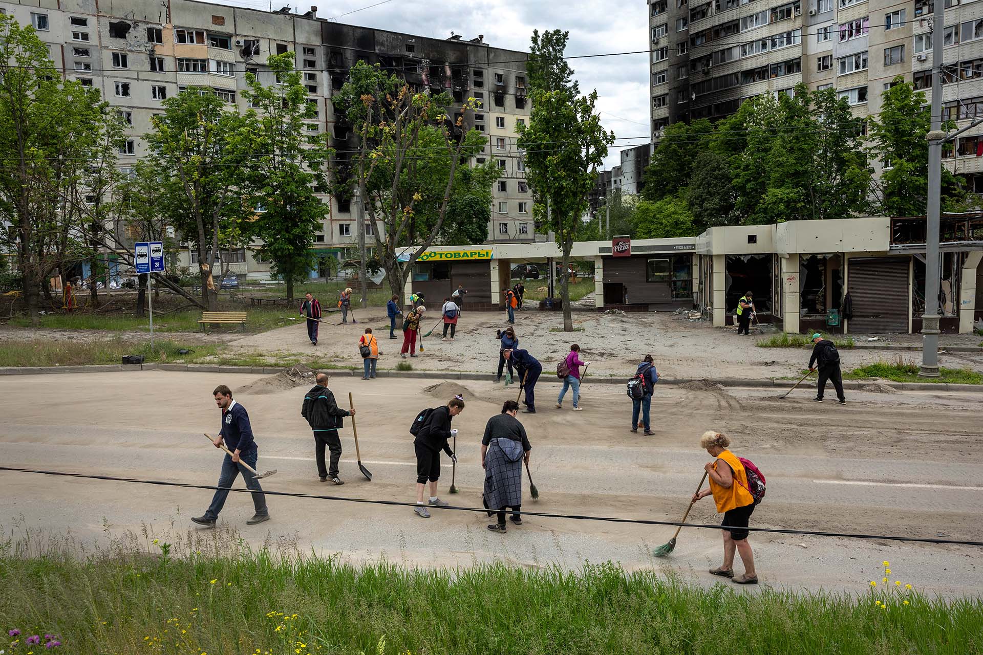Trabajadores del transporte público limpian los restos de escombros tras los bombardeos en un barrio de Kharkiv