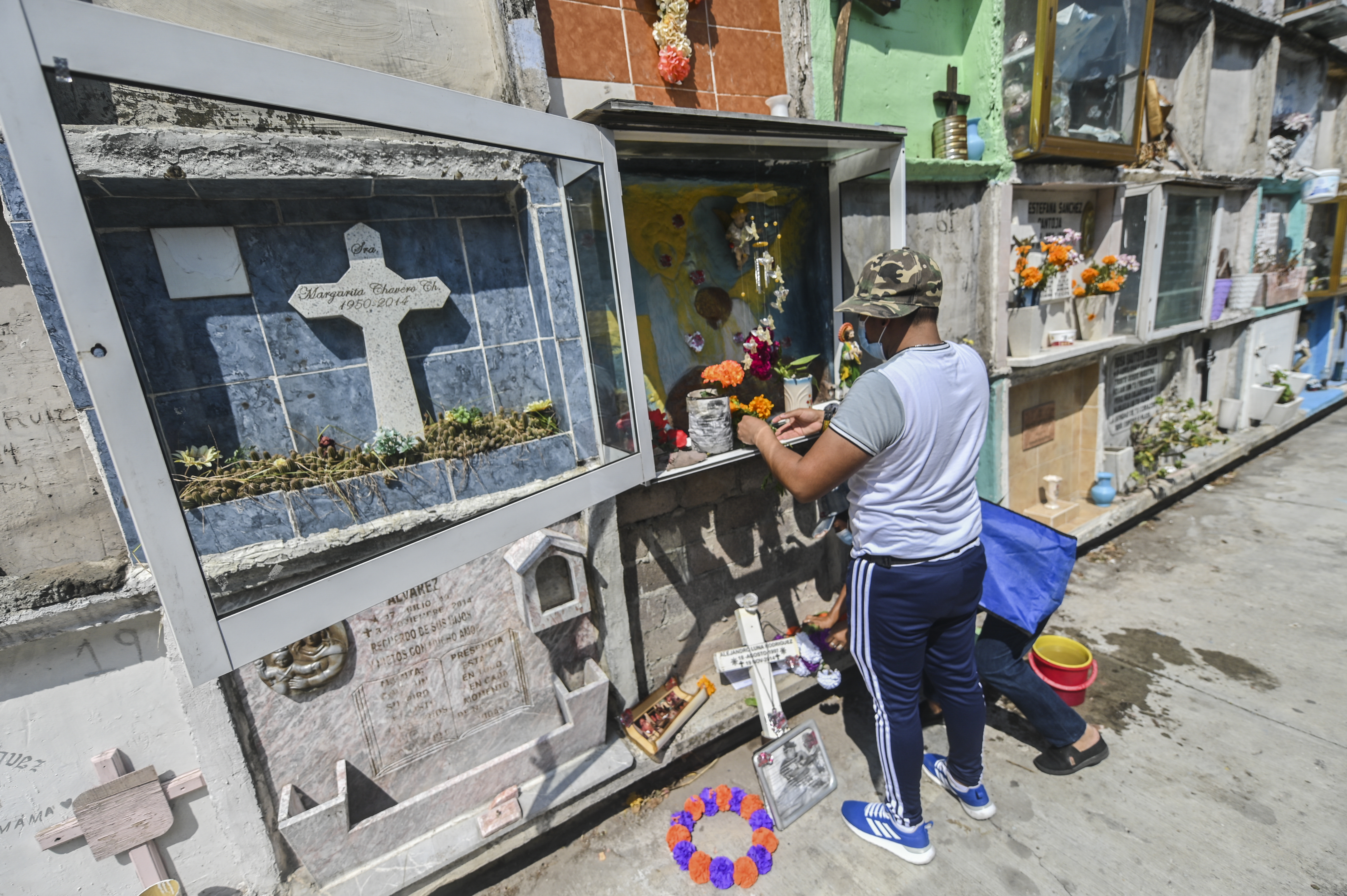Personas decoran la tumba de un familiar antes del Día de Muertos en el panteón municipal de Nezahualcóyotl, México, el 28 de octubre de 2020, en medio de la pandemia del coronavirus COVID-19.