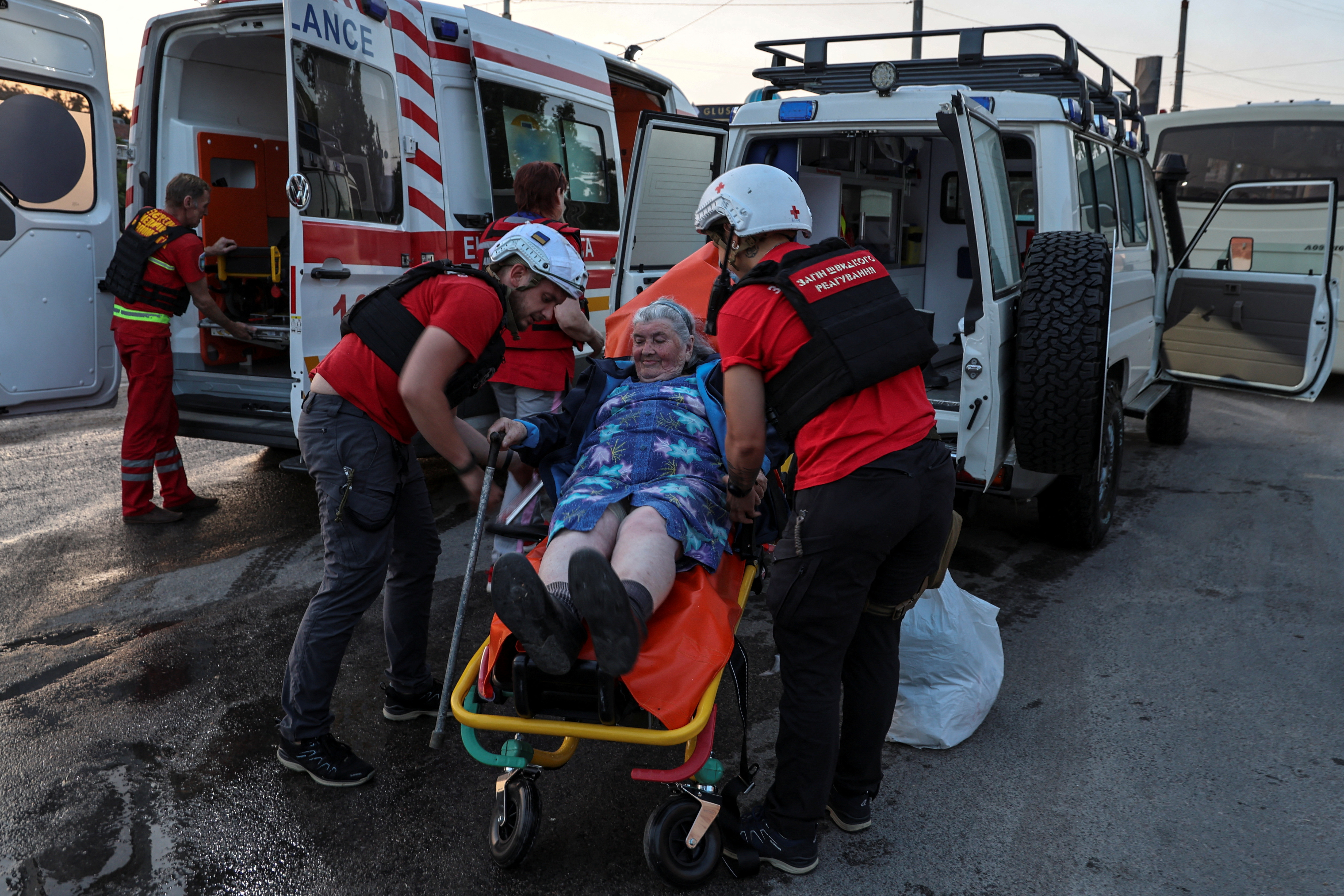 Un grupo de voluntarios de la Cruz Roja ayudan a subir a una mujer mayor a una ambulancia para ser evacuada.