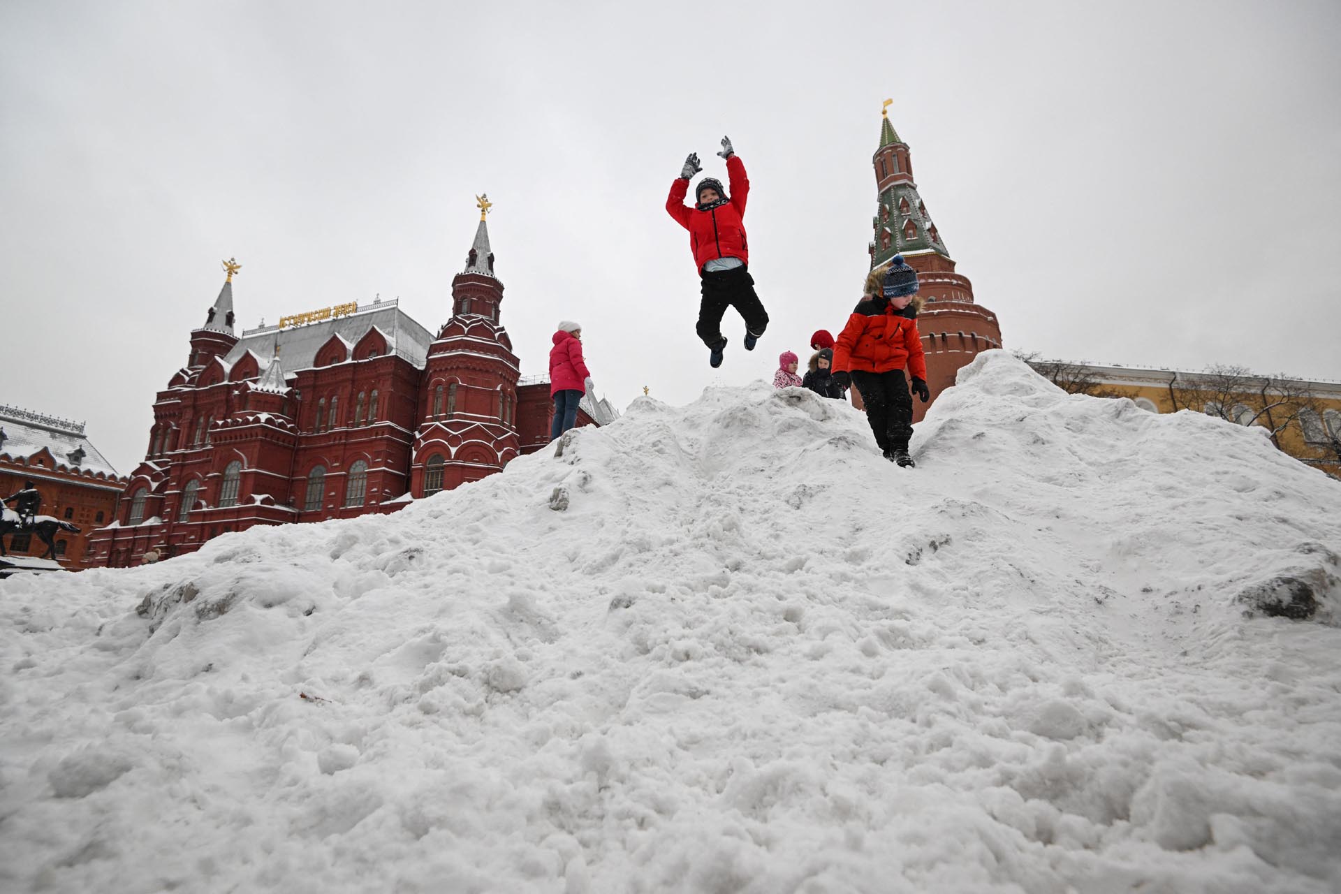 Los niños juegan con la nieve despejada de una plaza en Moscú el 17 de diciembre de 2022.
