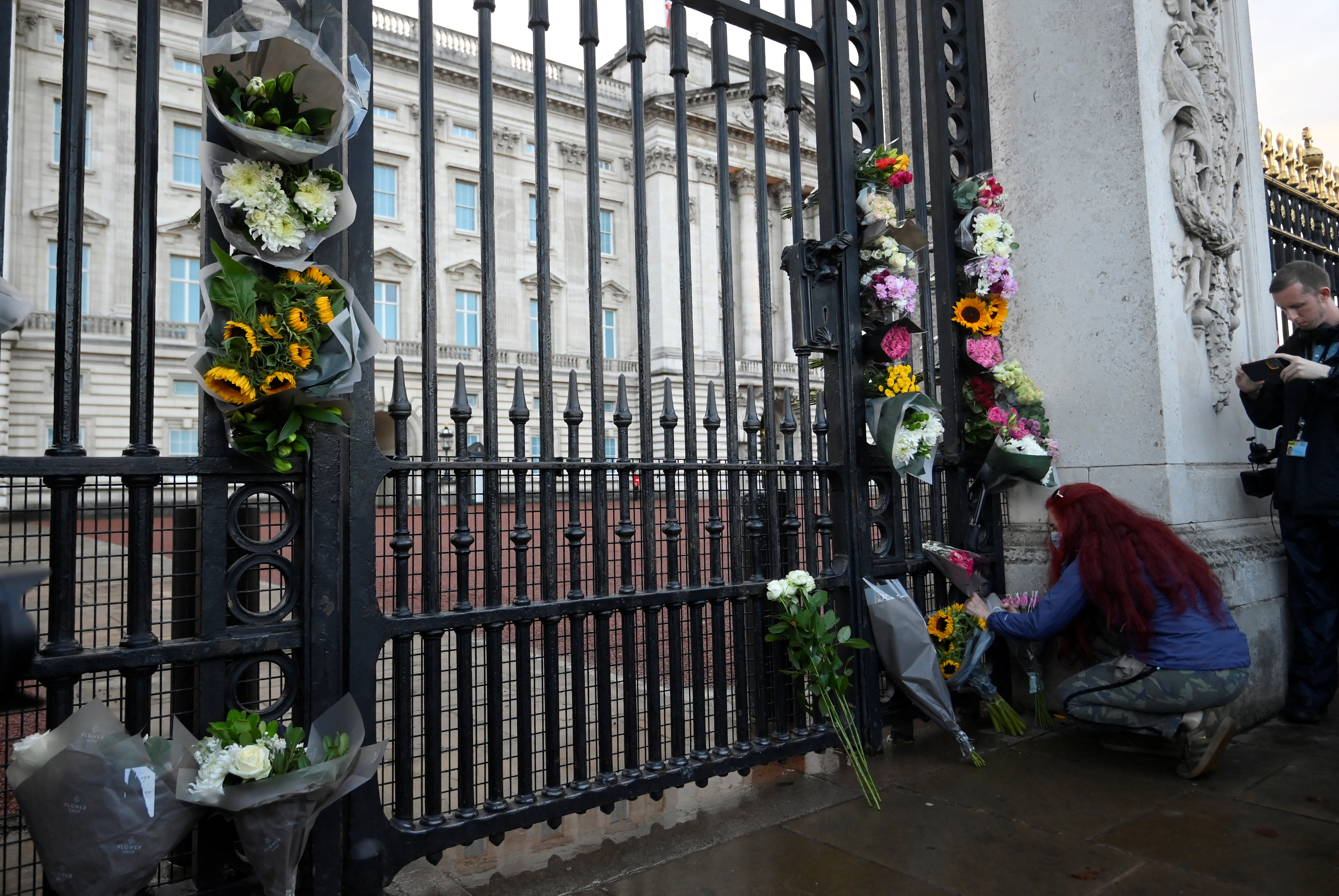 Una mujer coloca flores fuera del Palacio de Buckingham (REUTERS/Toby Melville)